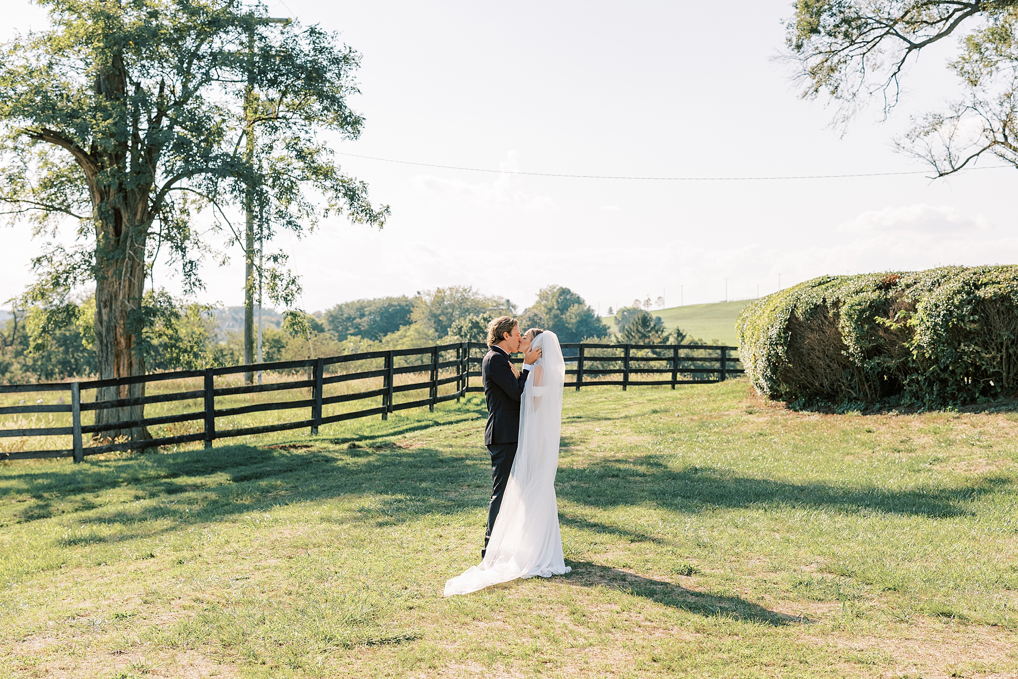 bride and groom kiss on hill near fence at Lauxmont Farms