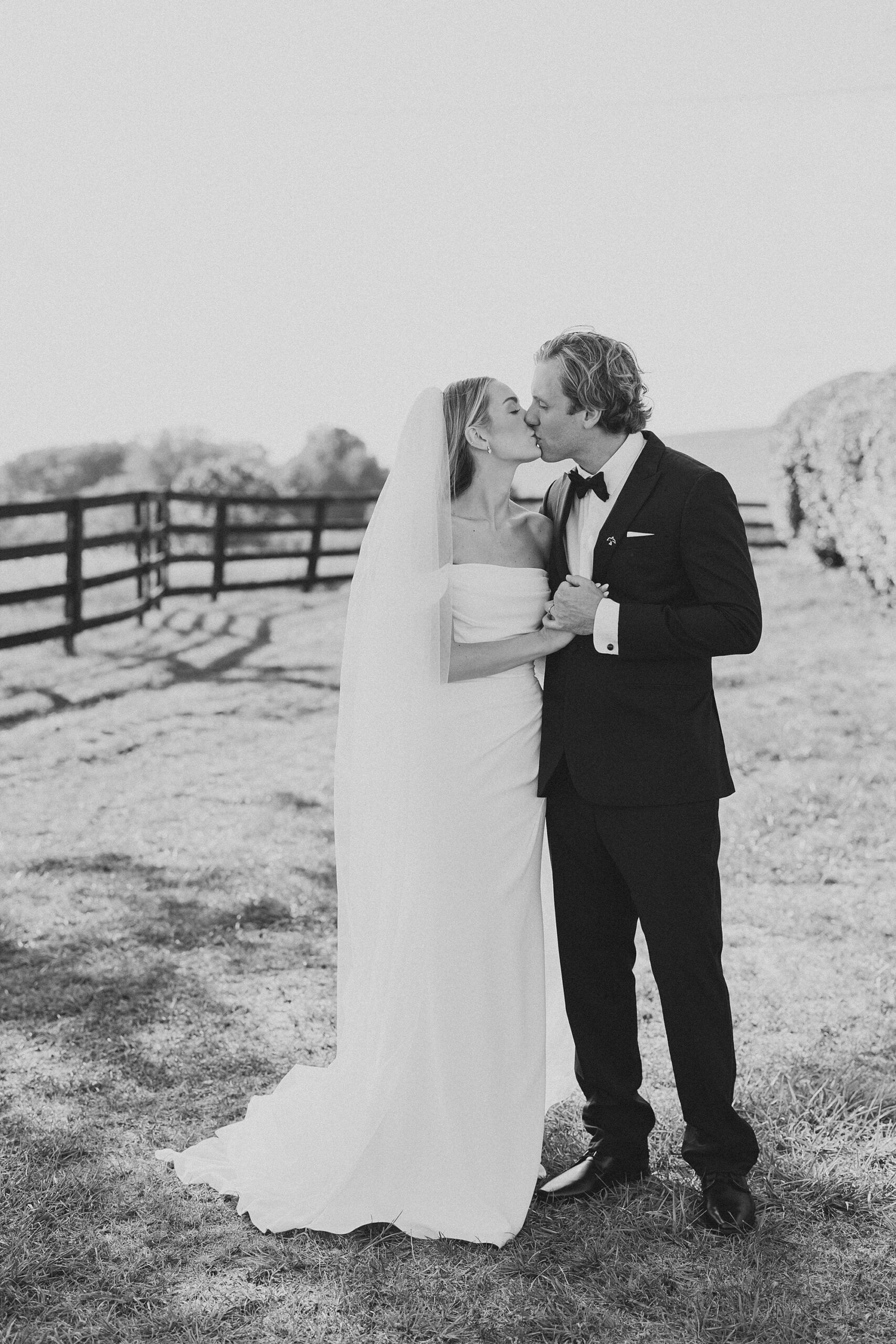 bride and groom kiss near black fence at Lauxmont Farms