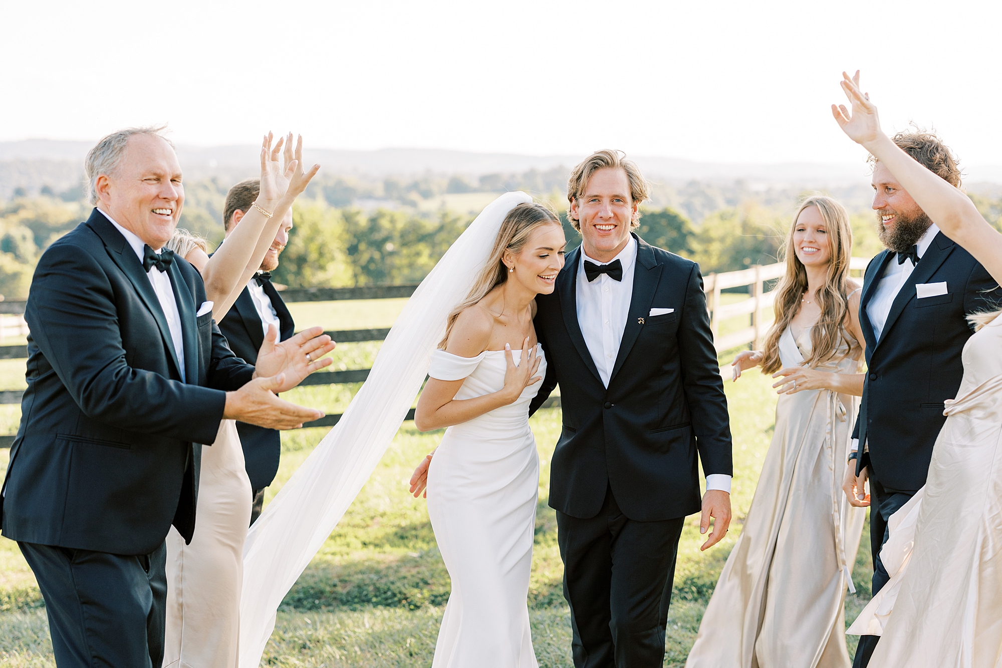 newlyweds hug between wedding party along wooden fence at Lauxmont Farms