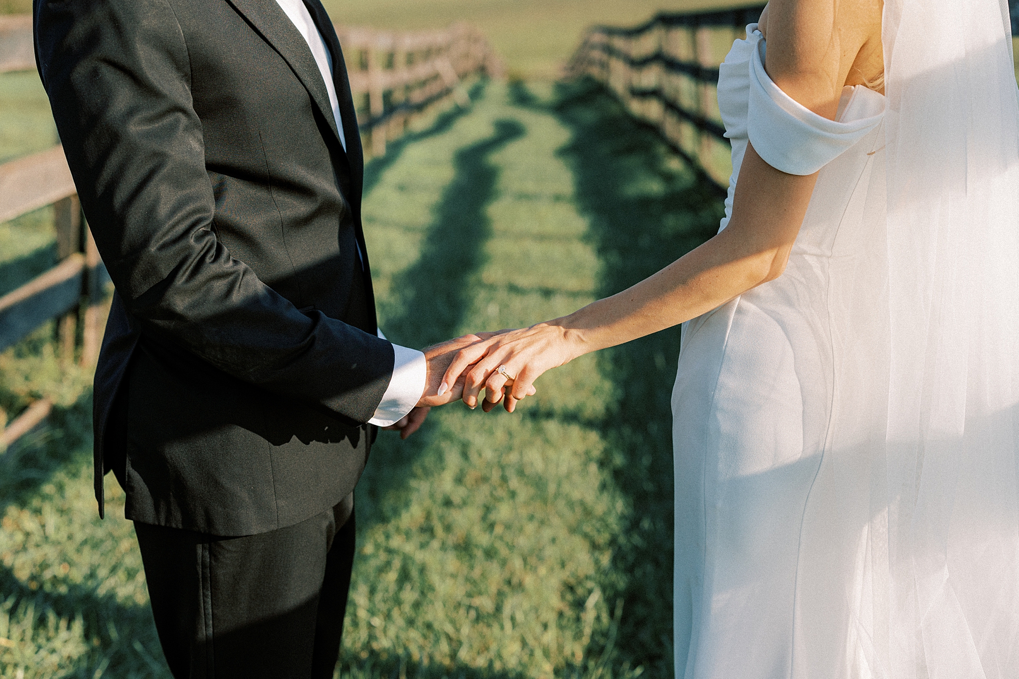 newlyweds hold hands along fence line at Lauxmont Farms