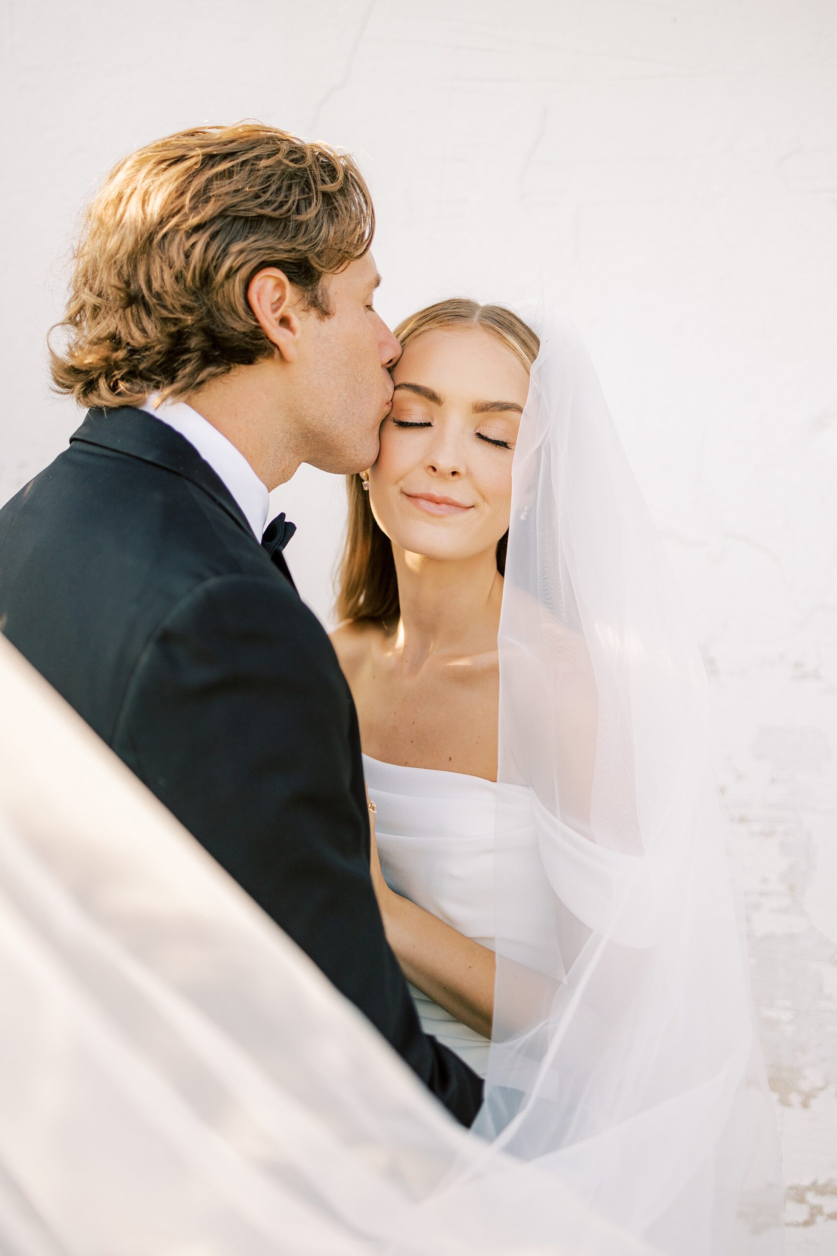 groom kisses bride's forehead with veil around them at Lauxmont Farms