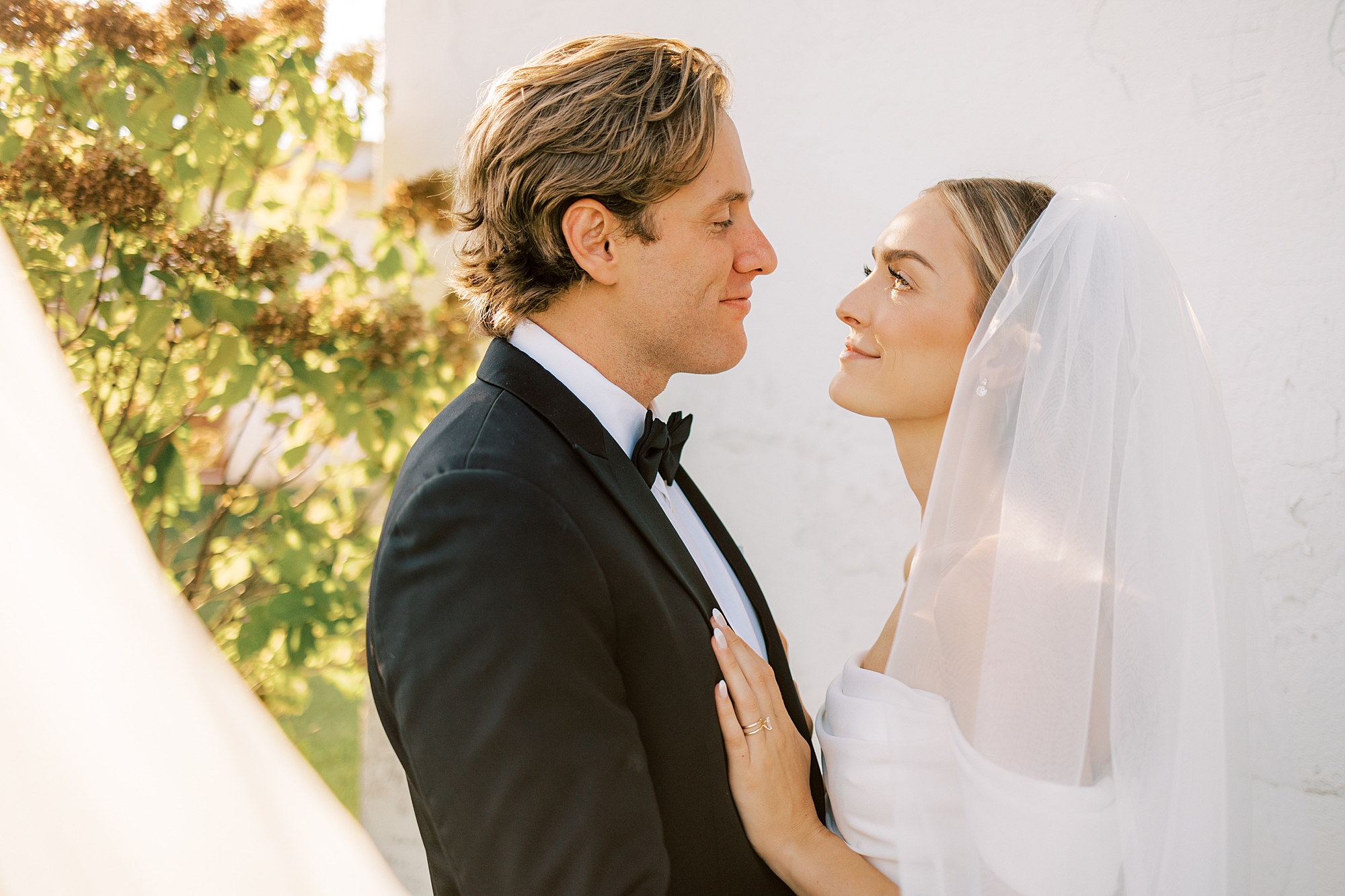 bride and groom smile together near white wall