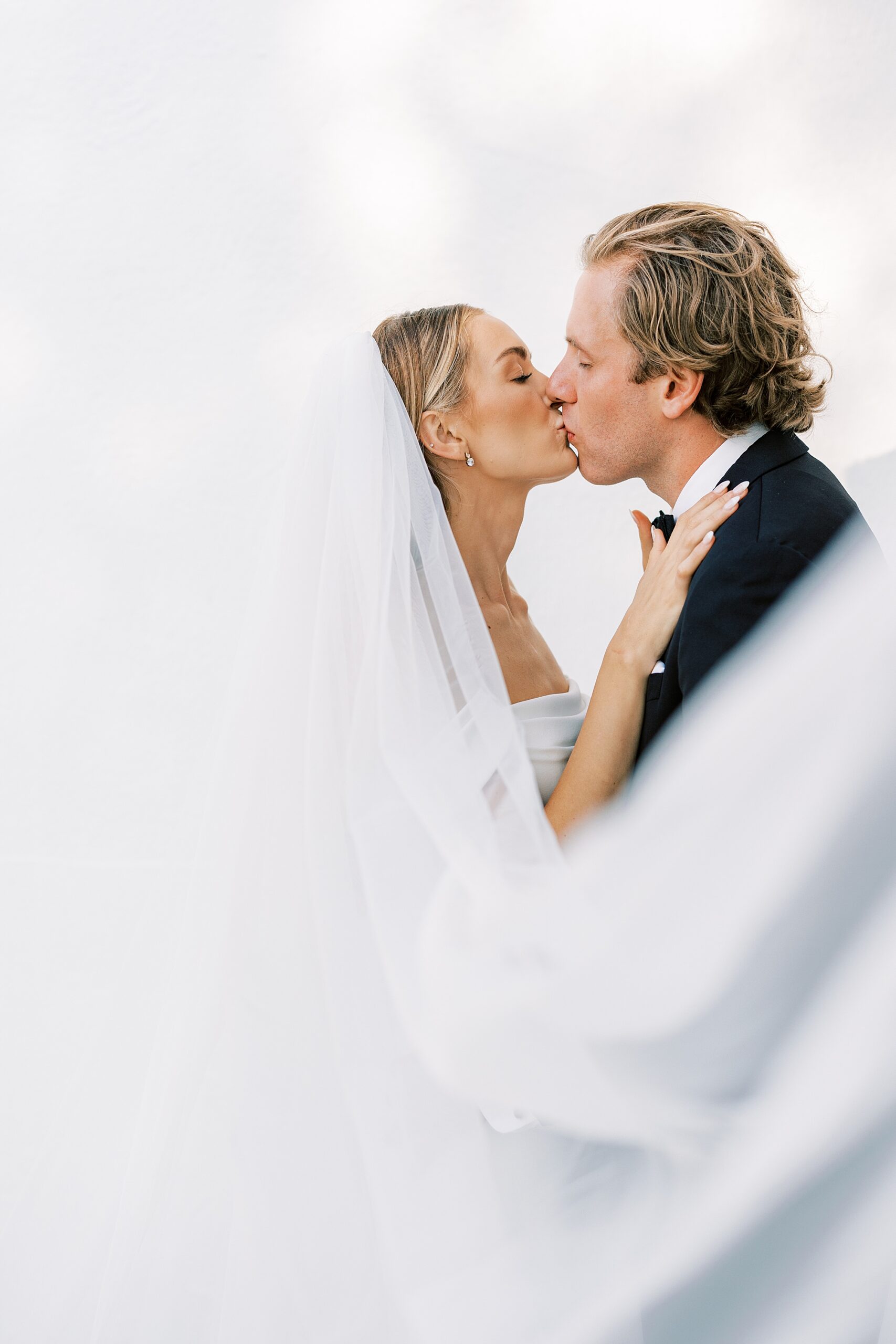 bride and groom kiss with veil floating around them at Lauxmont Farms