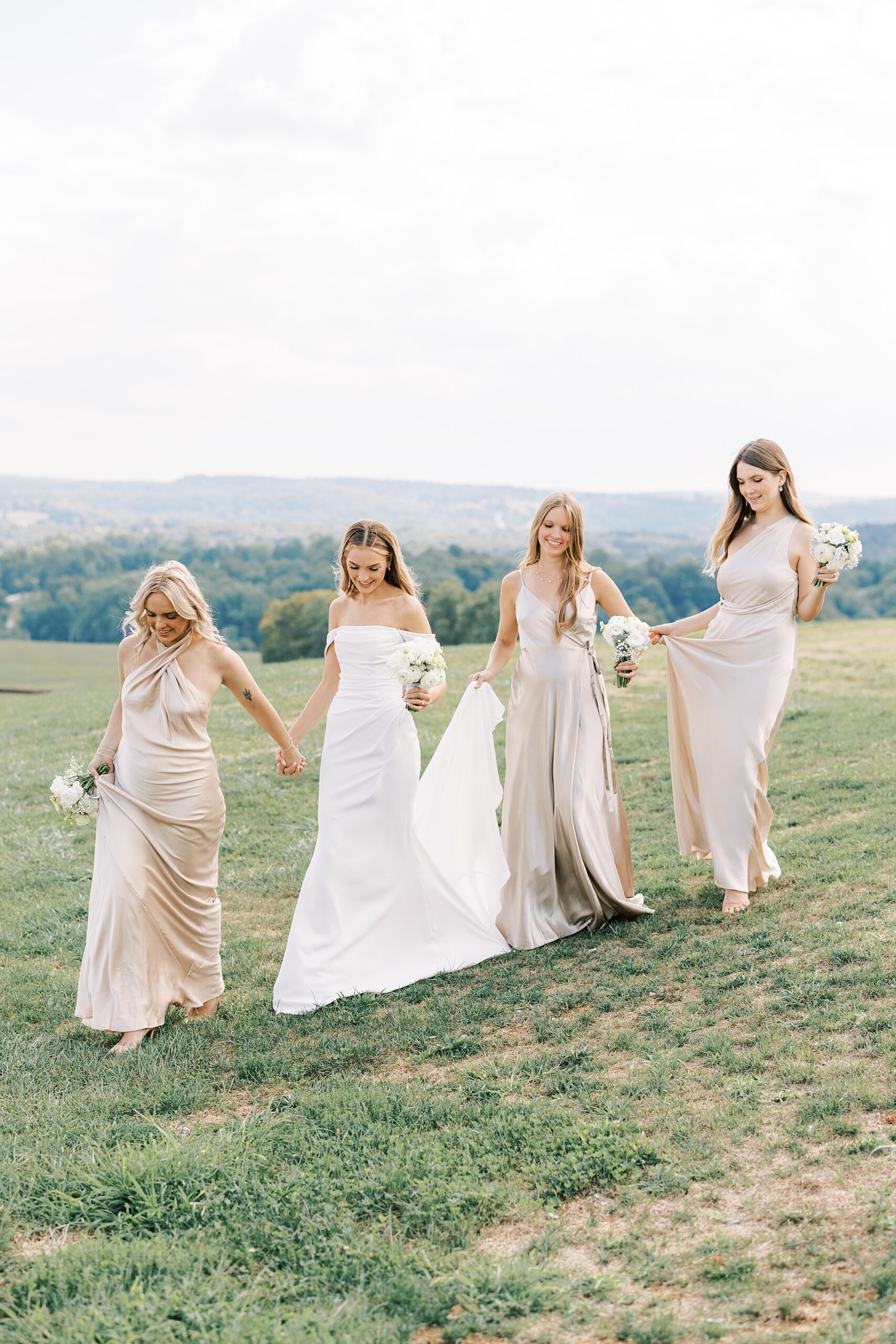 bride walks down hill with bridesmaid in champagne gown 