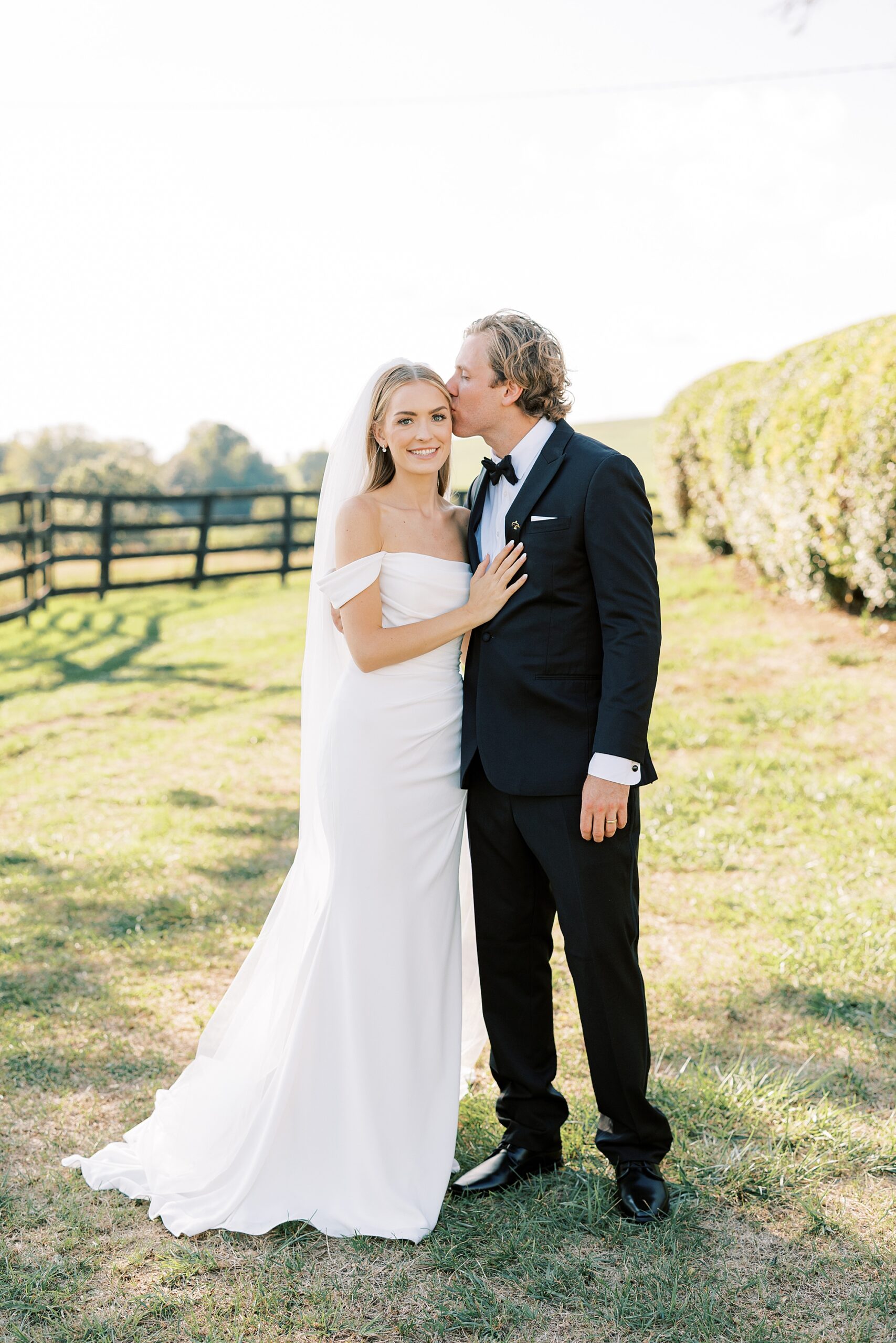 groom kisses bride's forehead standing on lawn at Lauxmont Farms