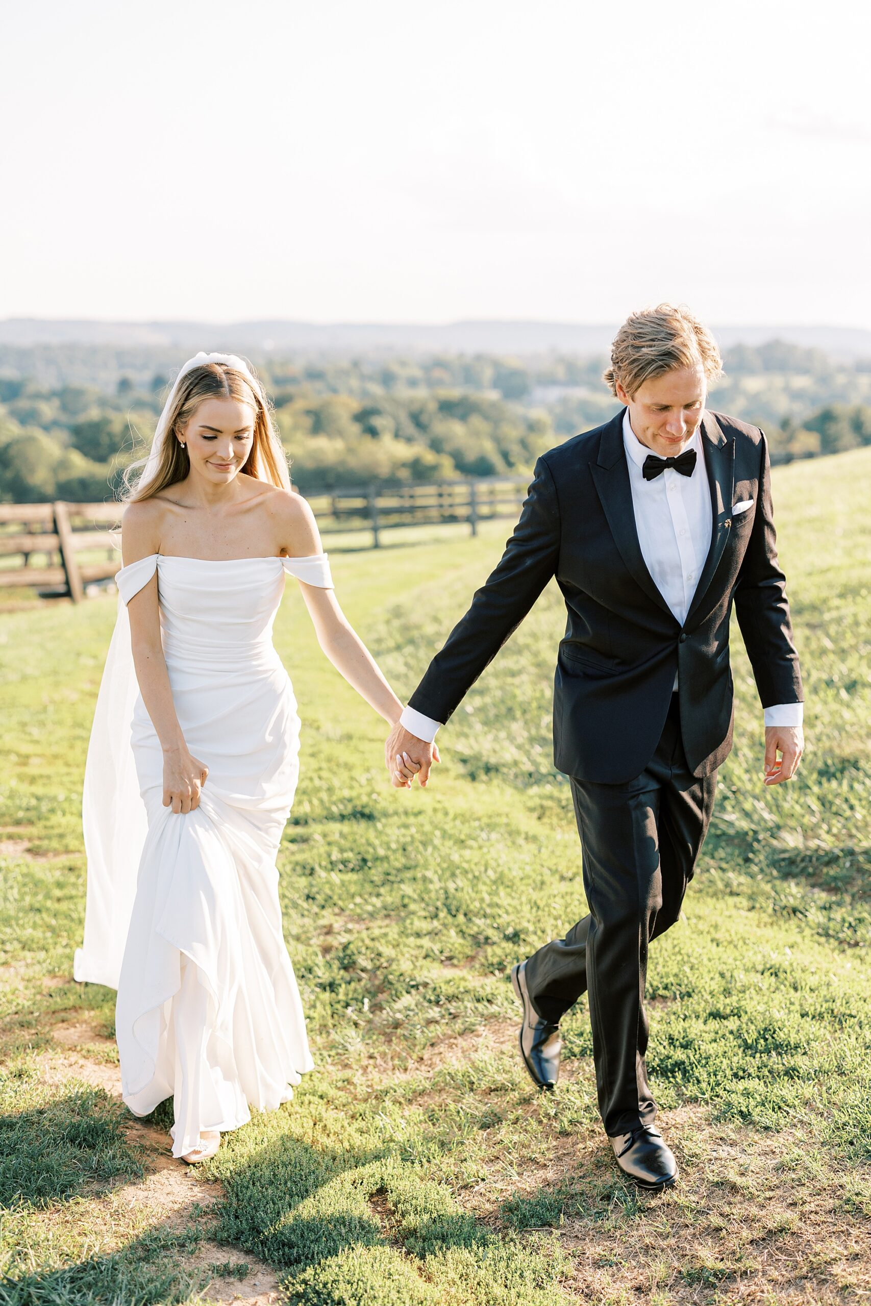 newlyweds hold hands walking on lawn at Lauxmont Farms