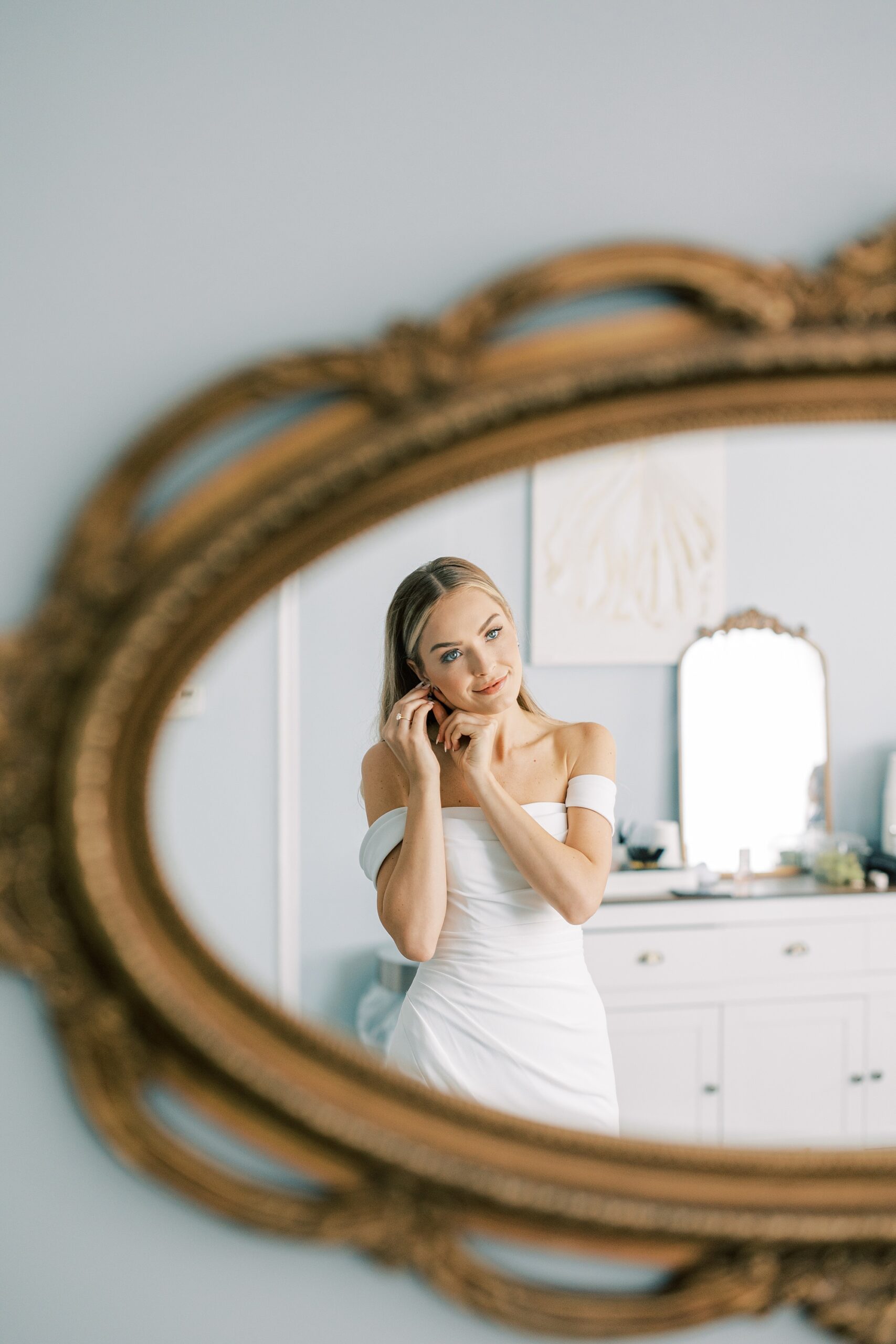 bride adjusts earring looking in gold framed mirror at Lauxmont Farms