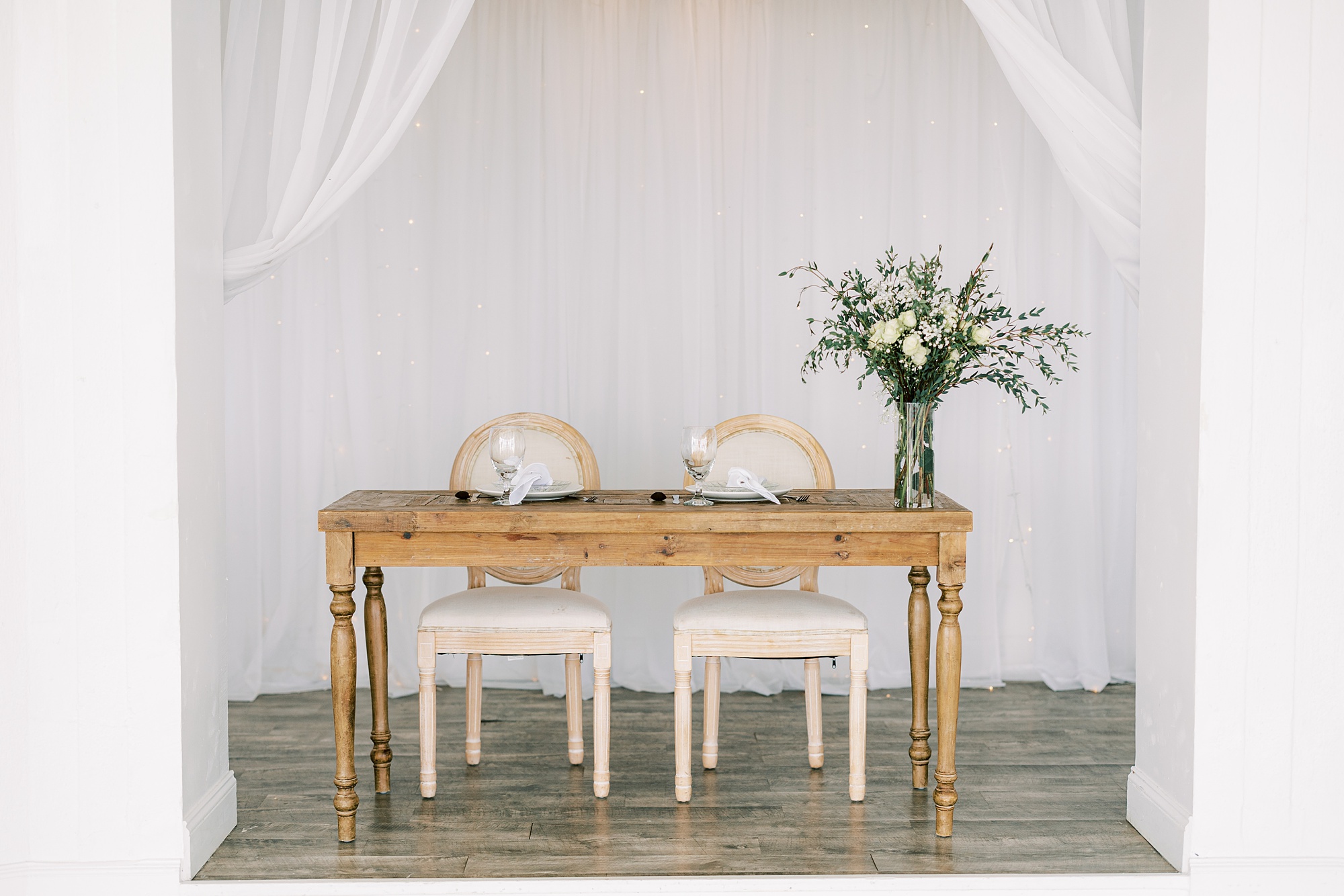 sweetheart table with wooden table and ivory chairs 