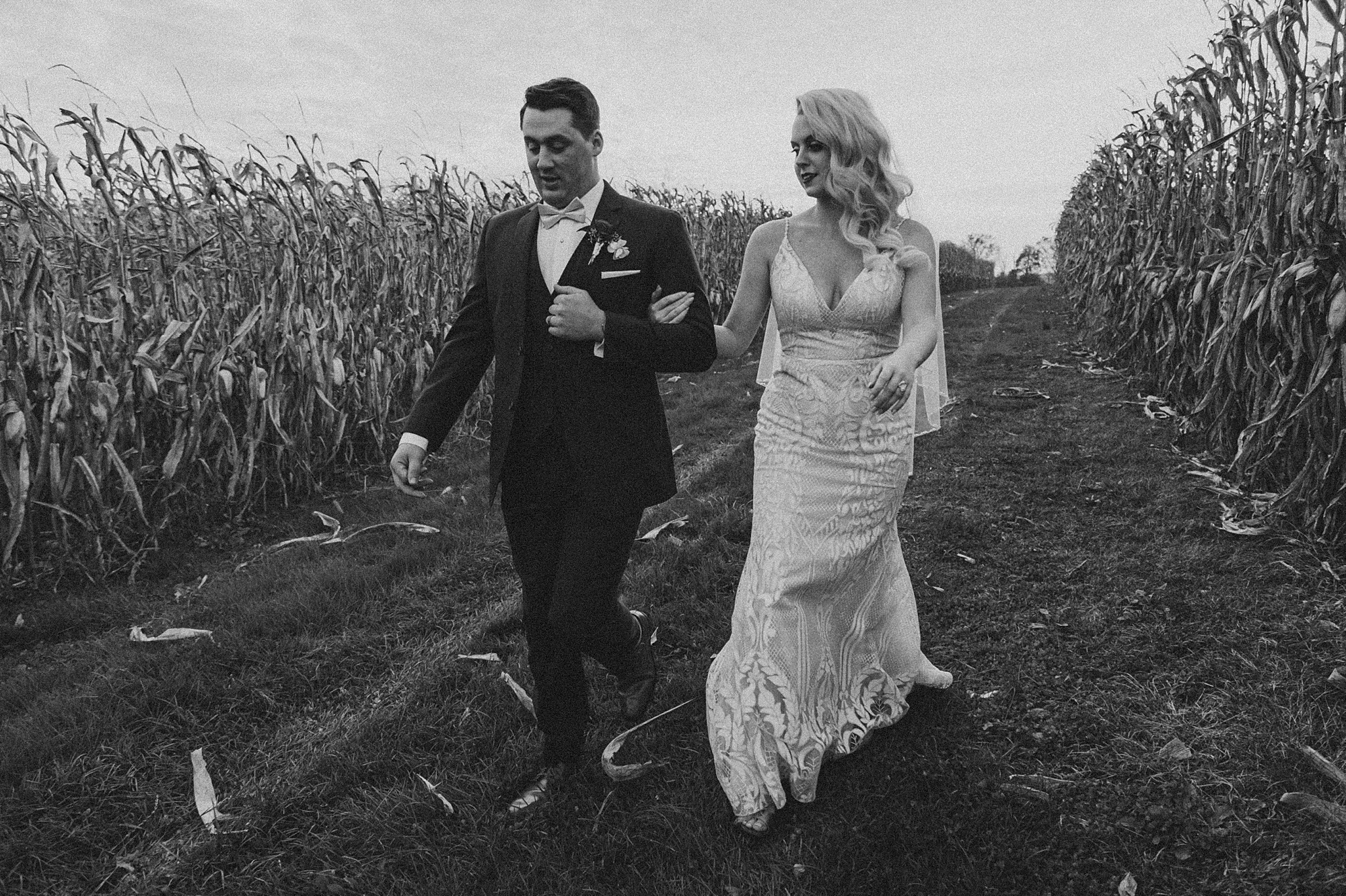 bride and groom hold hands walking through cornfields at Osbornia Farm