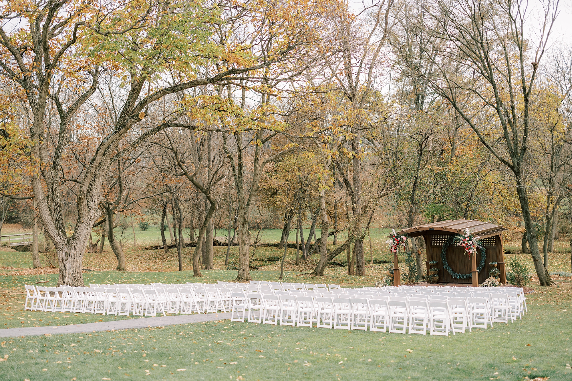 fall wedding ceremony with white chairs on lawn at Osbornia Farm