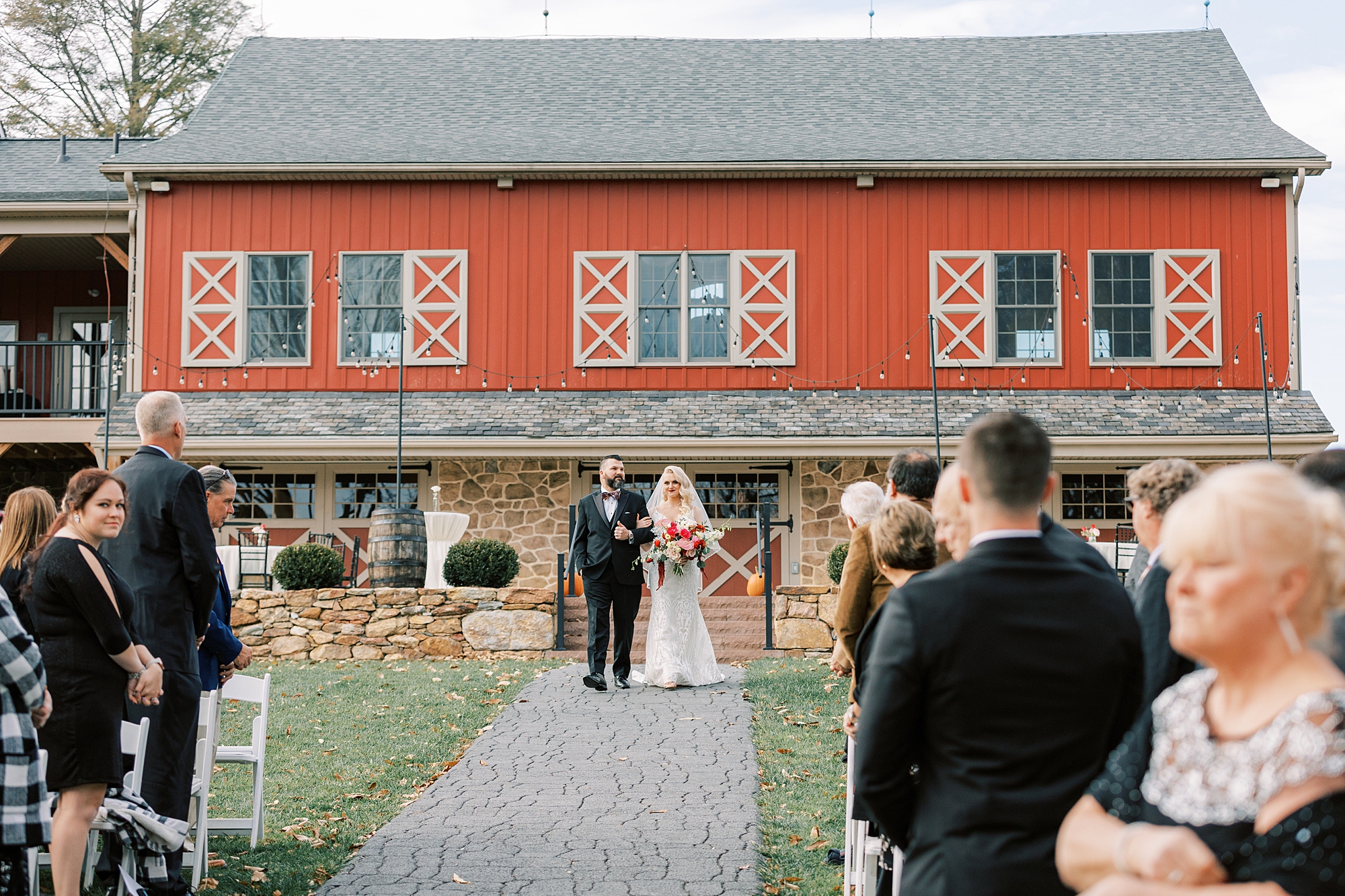 bride enters wedding ceremony with brother during fall wedding day at Osbornia Farm