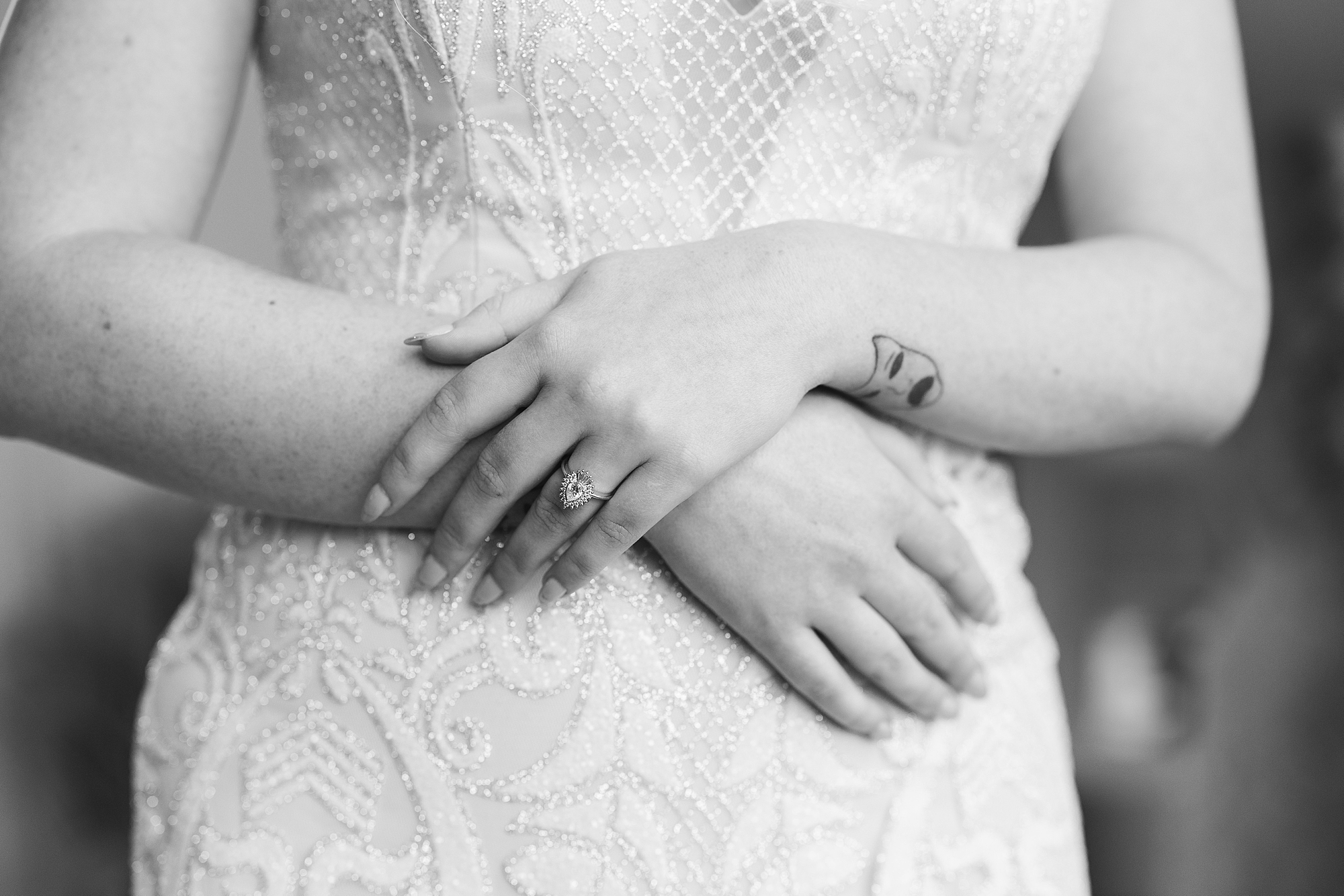 bride holds hands in front of lace wedding dress