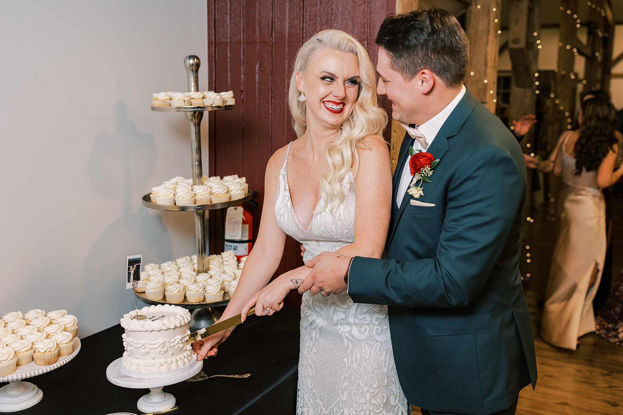 groom hugs bride from behind during cake cutting at fall wedding reception 