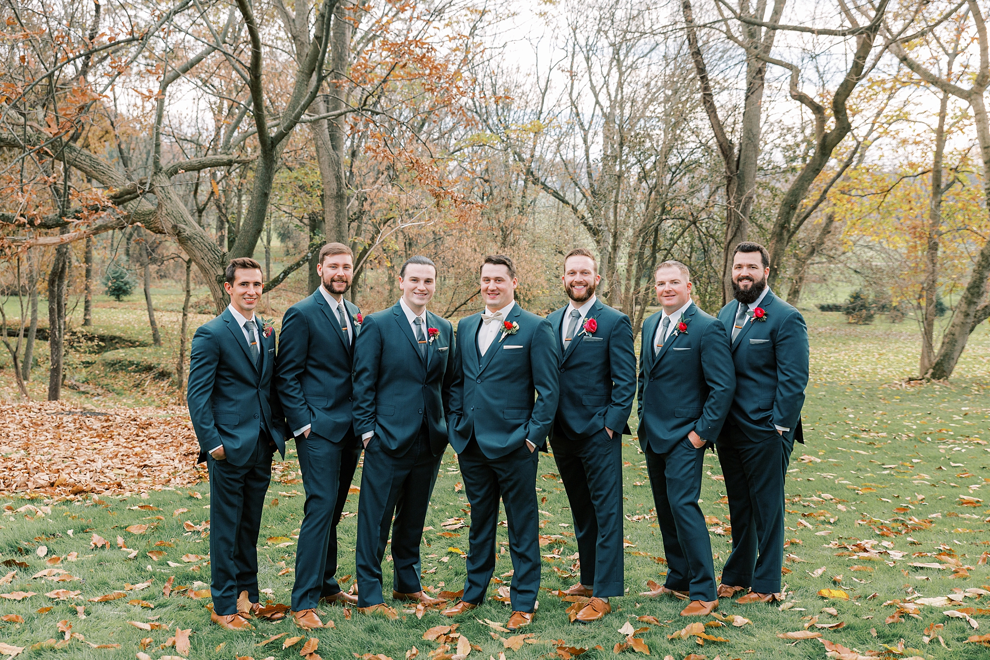 groom and groomsmen in navy suits stand on lawn at Osbornia Farm