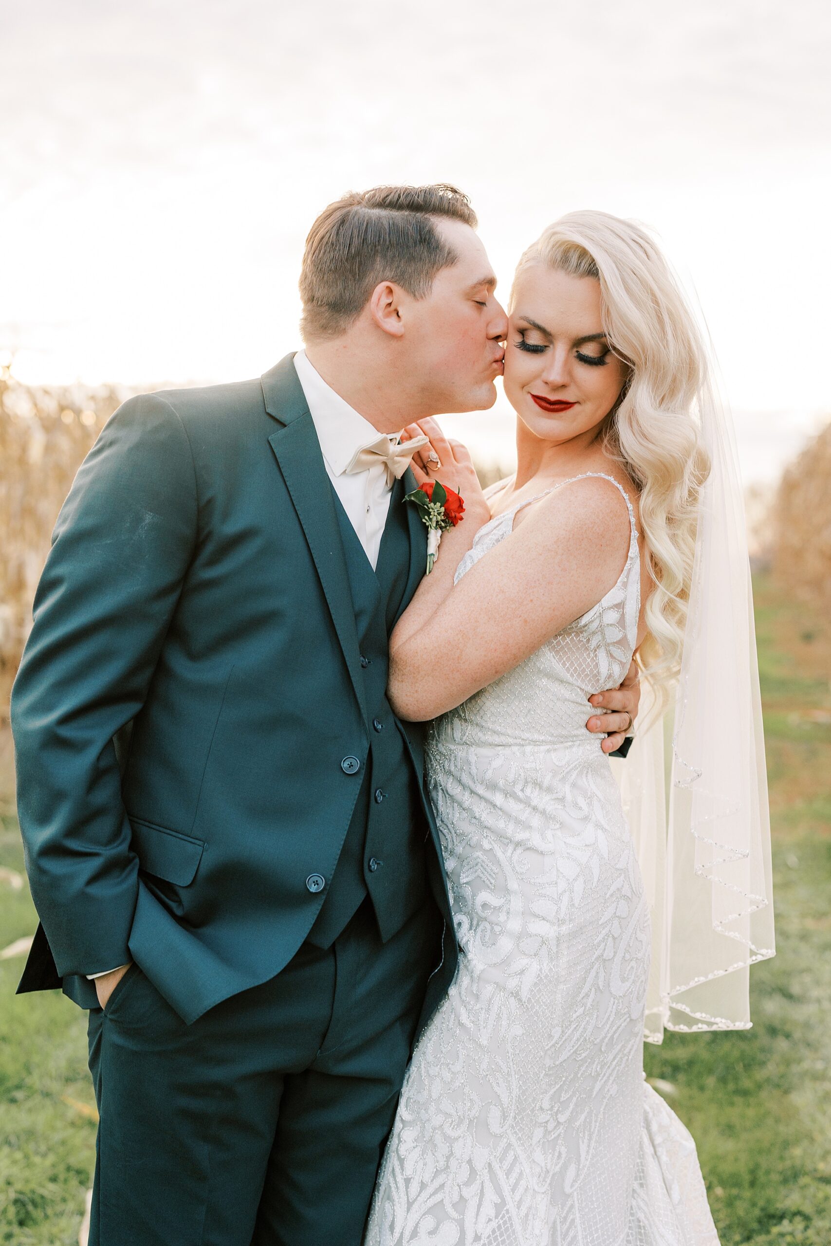 groom kisses bride's cheek during fall wedding