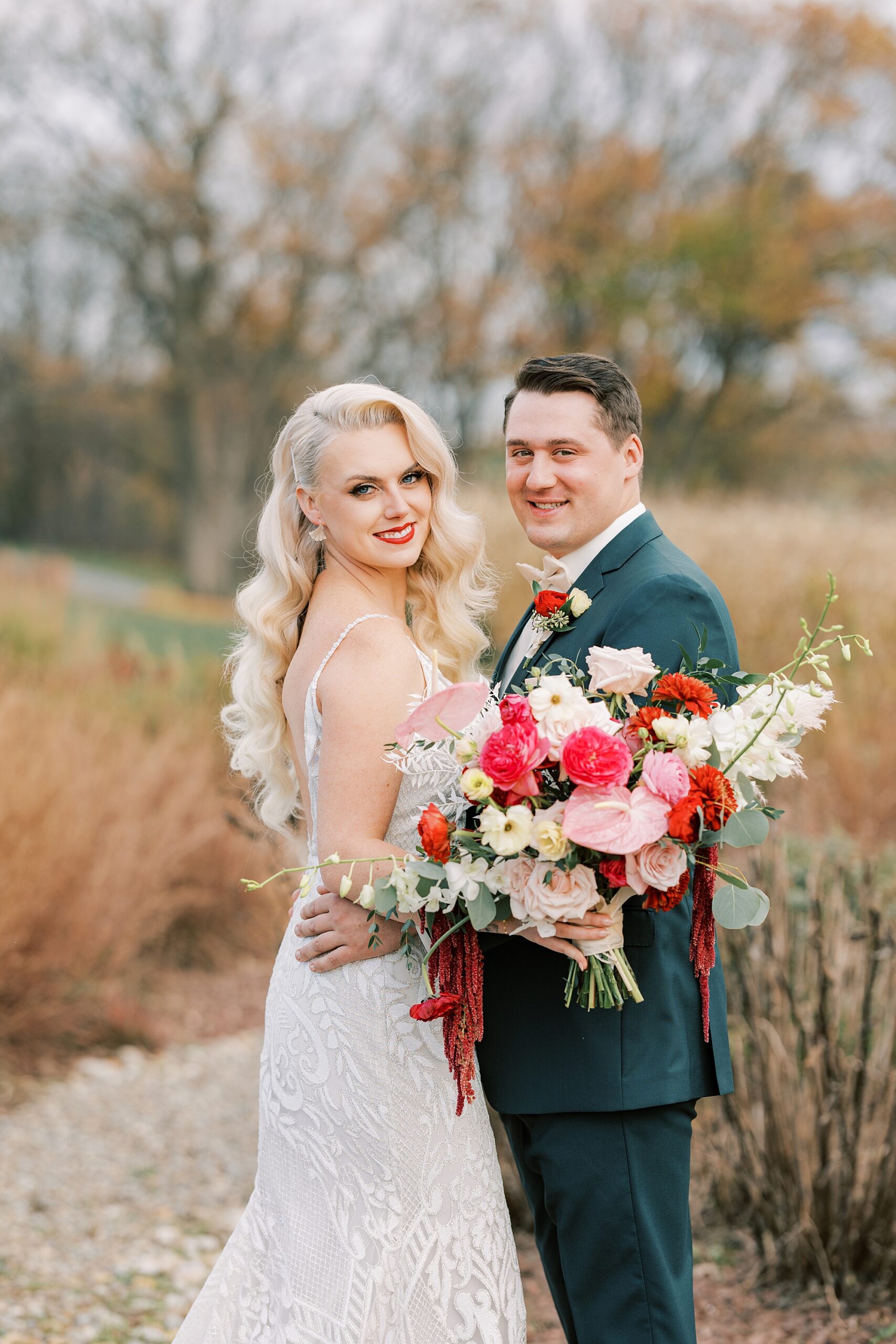 newlyweds hug while bride holds pink and white bouquet on groom's arm 