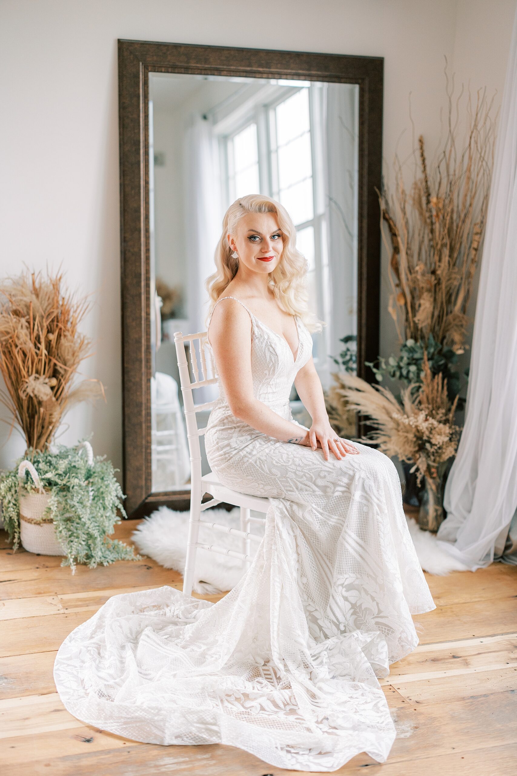 bride sits on chair in front of mirror in suite at Osbornia Farm