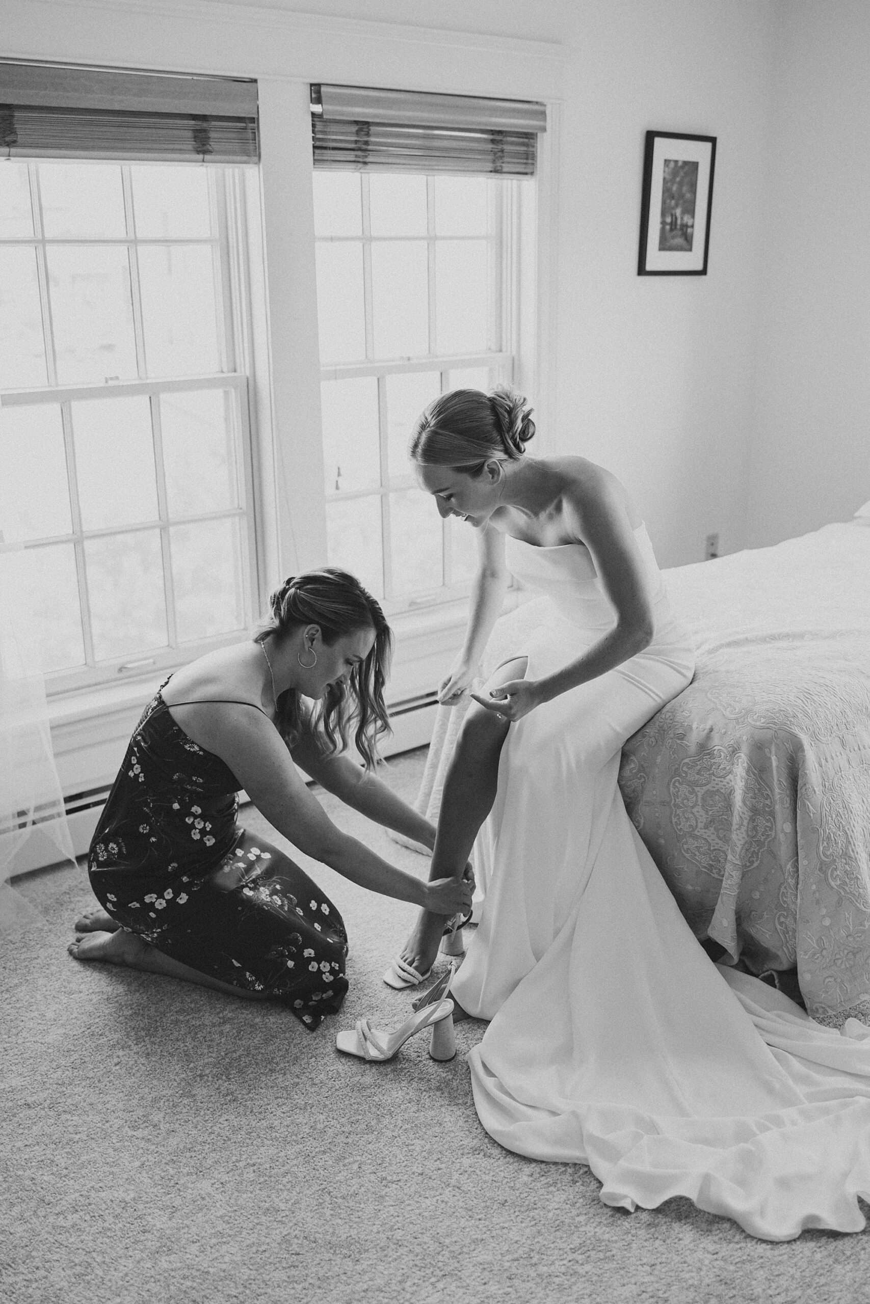 bridesmaid kneels to help bride put on shows in NJ home