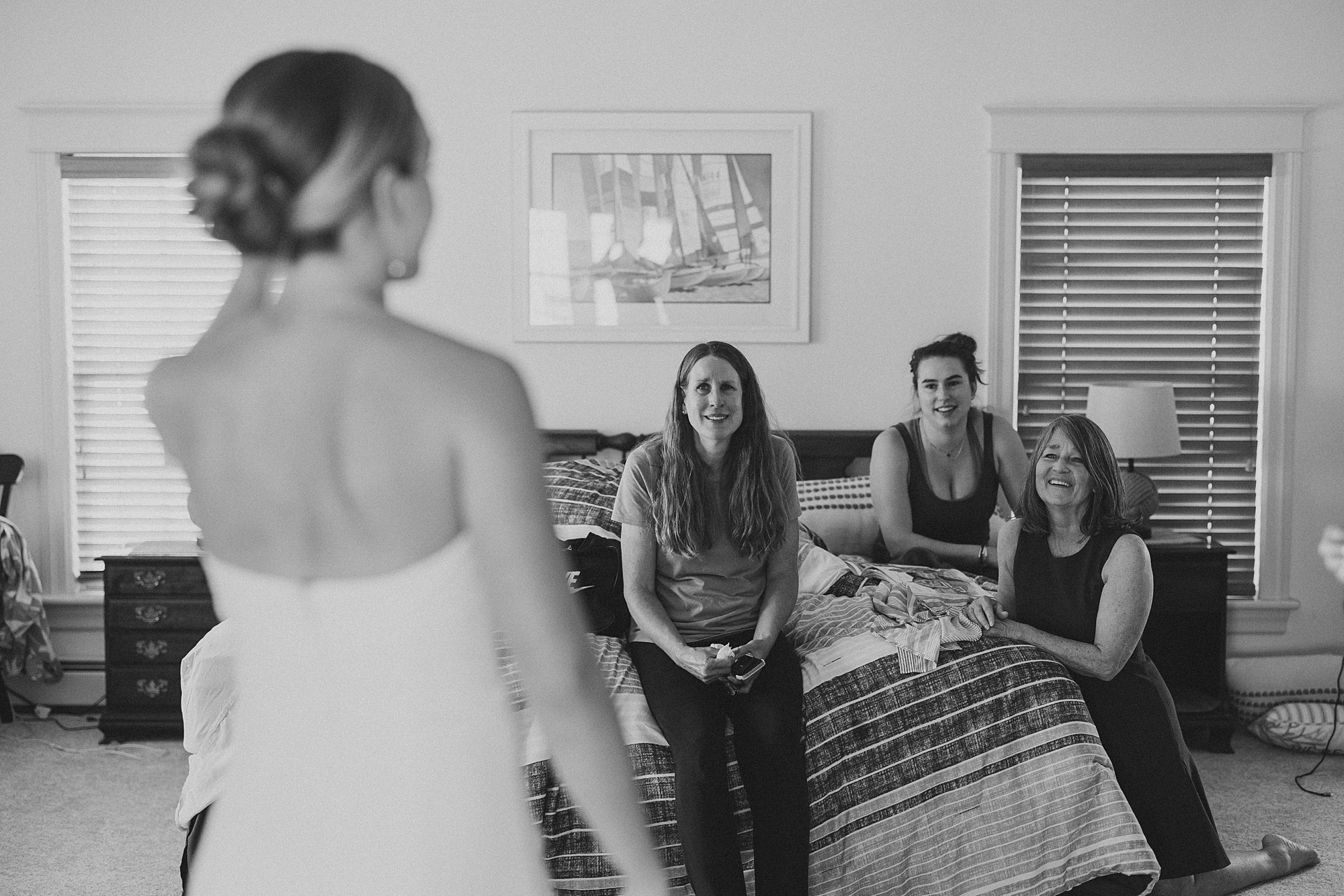 bridesmaids talk to bride sitting on bed during prep for NJ wedding