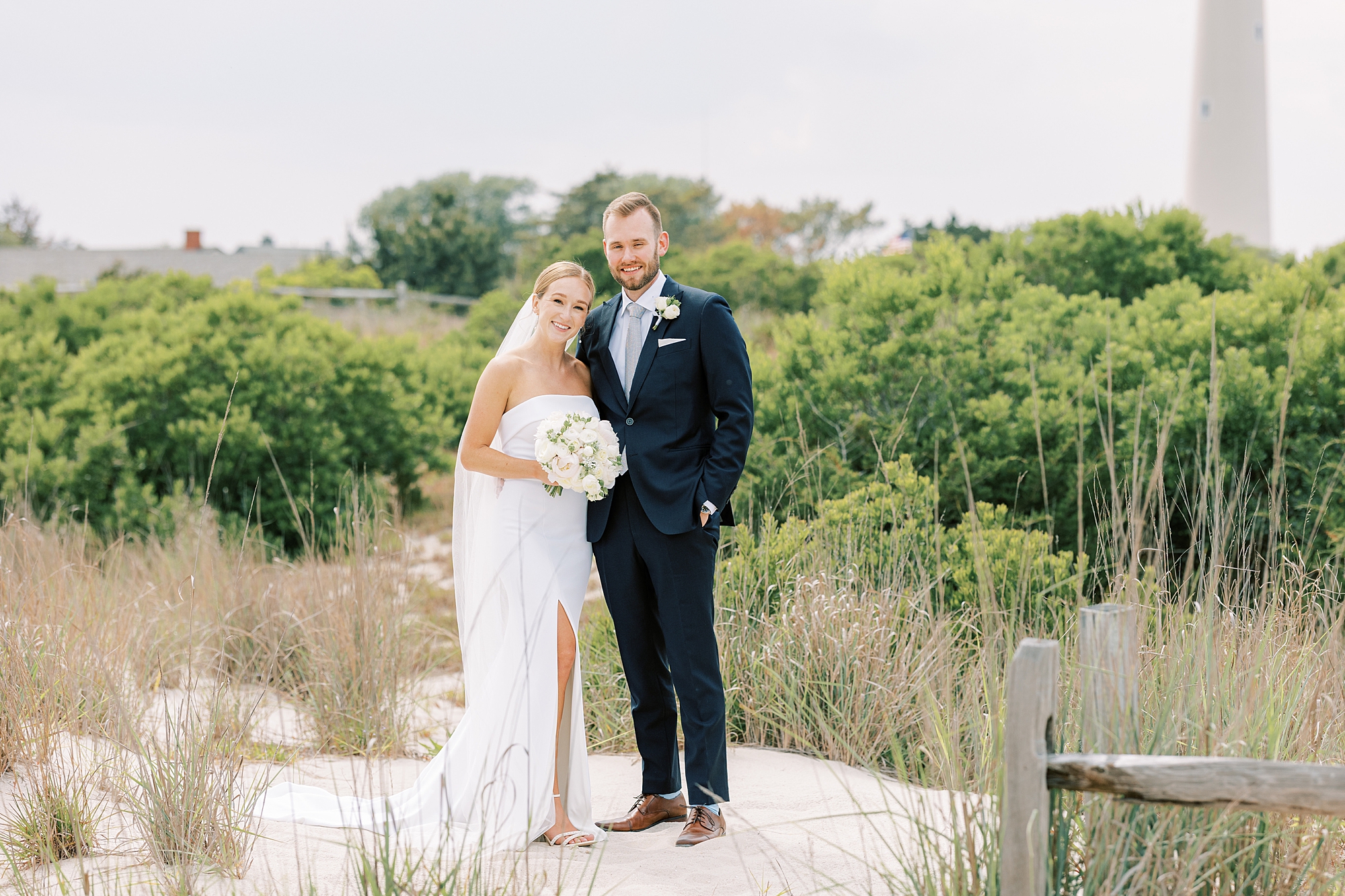bride and groom stand on sand dune on Cape May NJ beach 