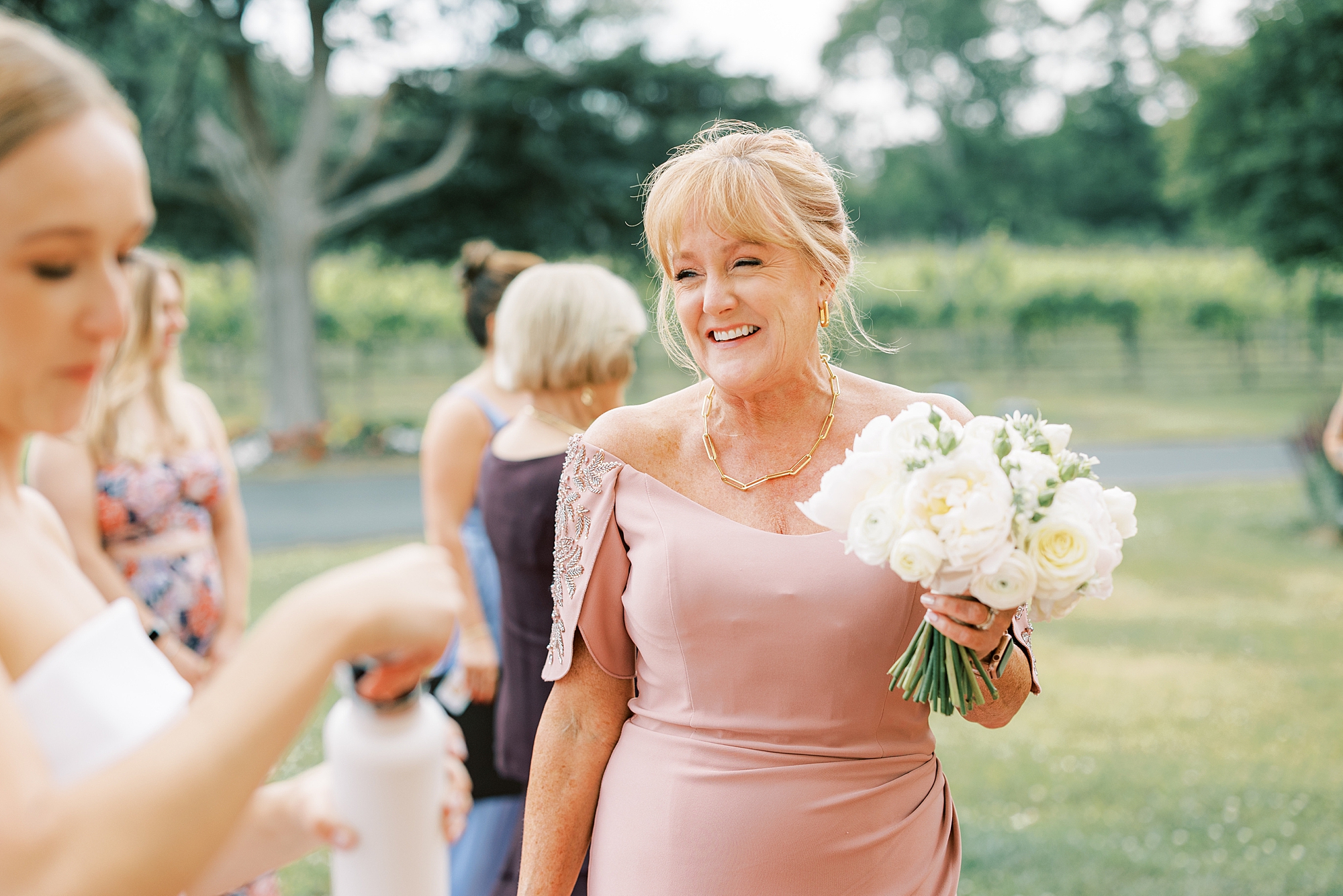 woman in pink dress holds bride's bouquet at Willow Creek Winery