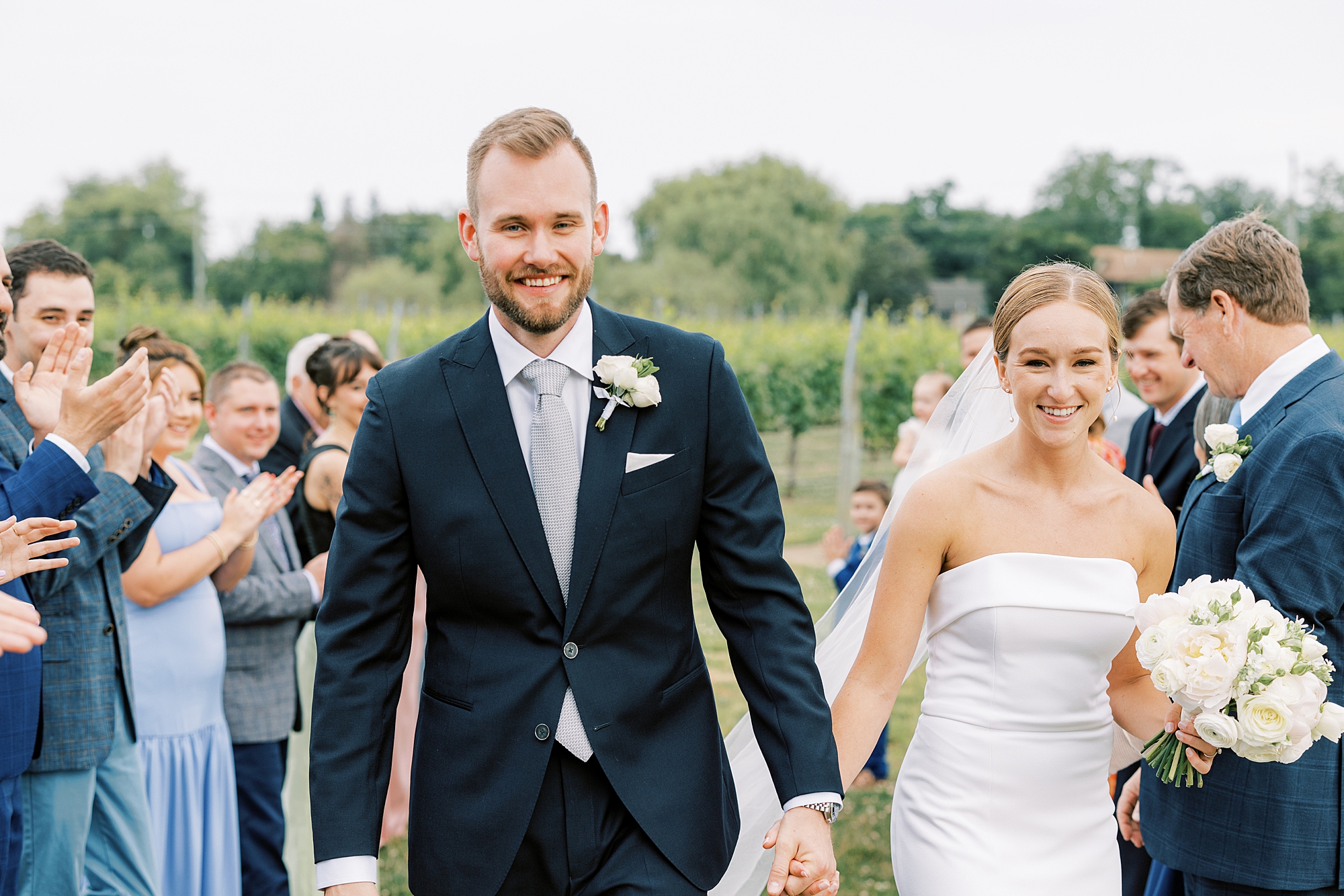bride and groom hold hands walking up aisle at Willow Creek Winery
