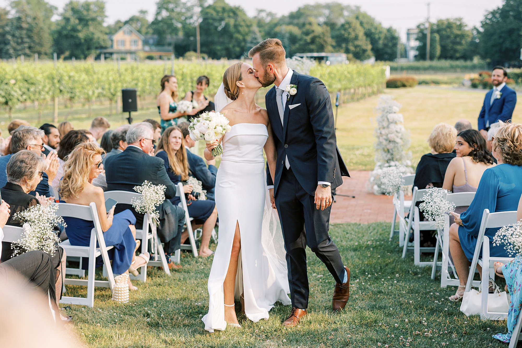 newlyweds kiss in aisle leaving wedding ceremony at Willow Creek Winery