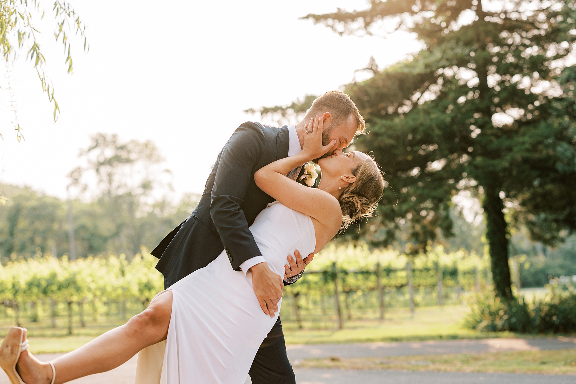 groom kisses bride dipping her backwards in front of Willow Creek Winery vines