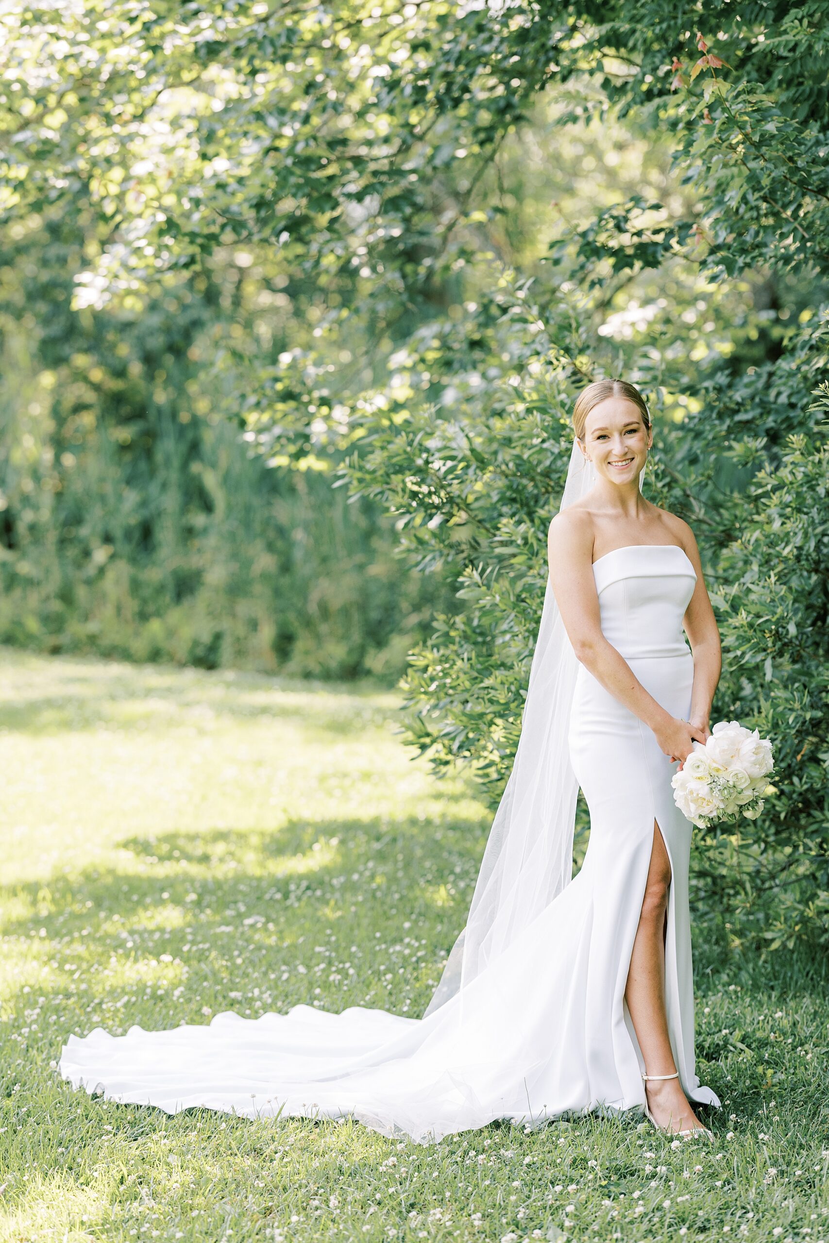bride holds bouquet of ivory bouquet in strapless wedding gown