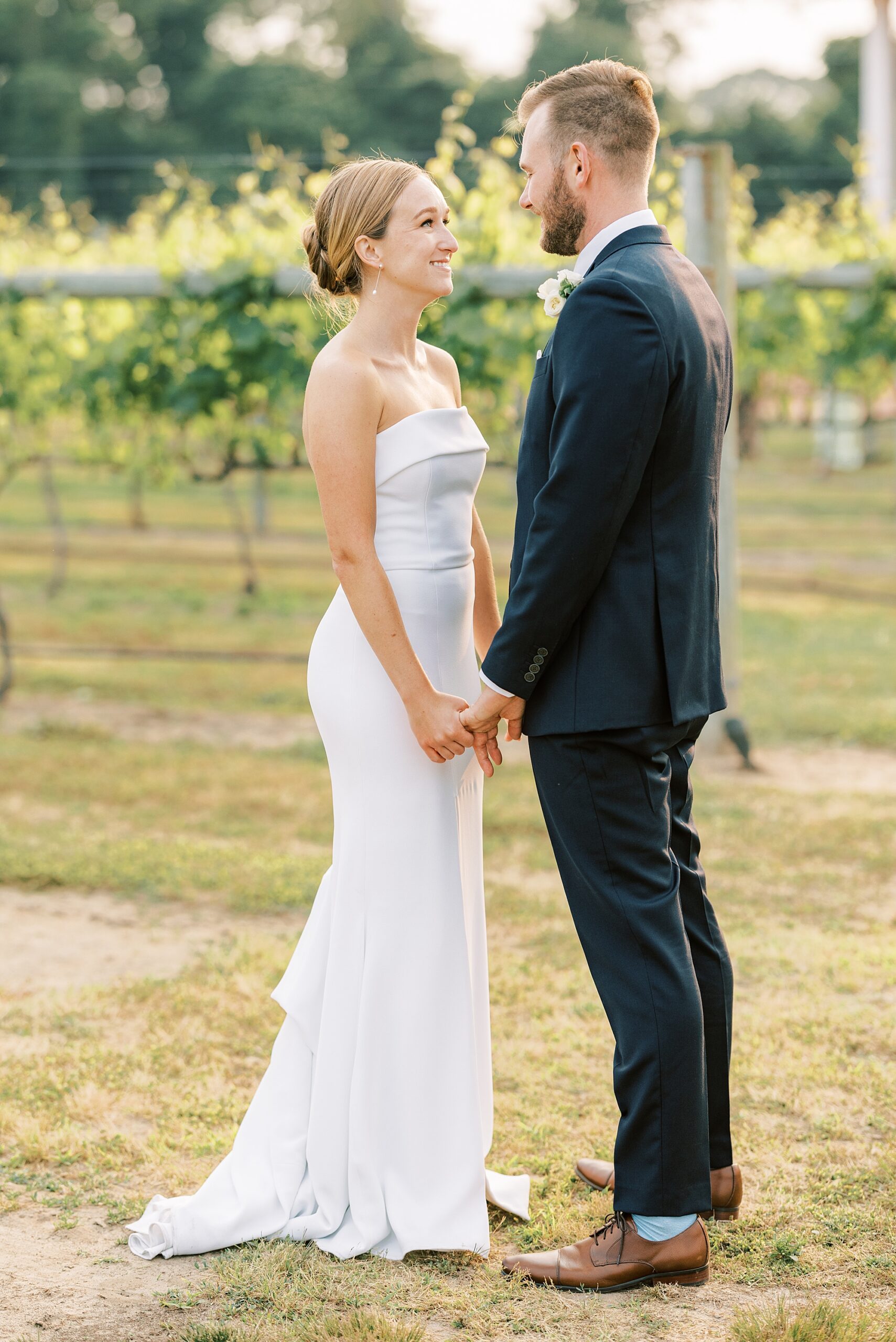 bride and groom hold hands standing in front of vines at Willow Creek Winery
