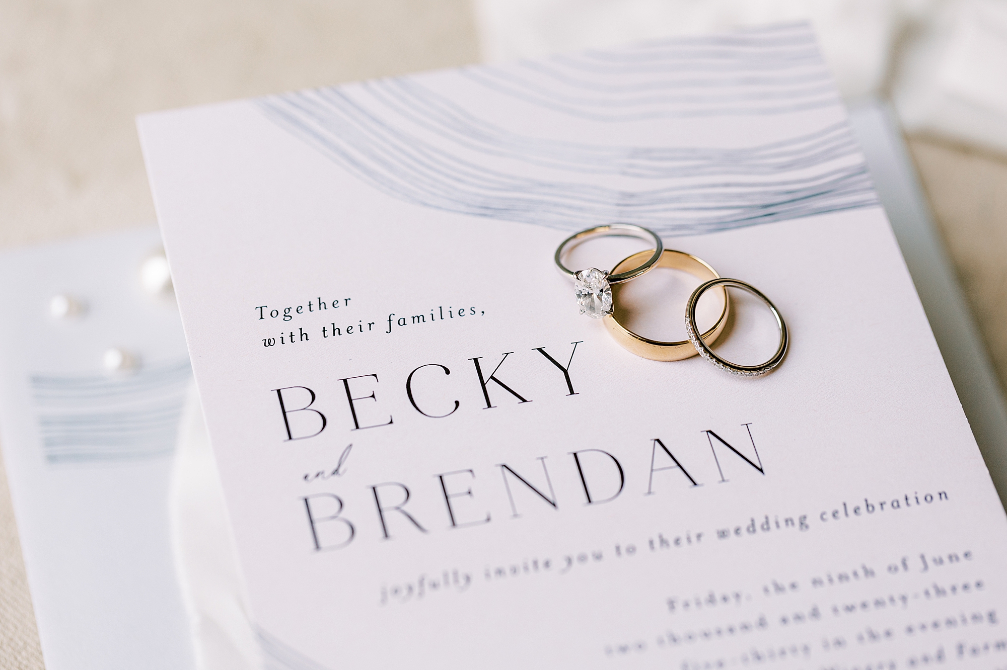 wedding bands lay on blue and white invite suite 