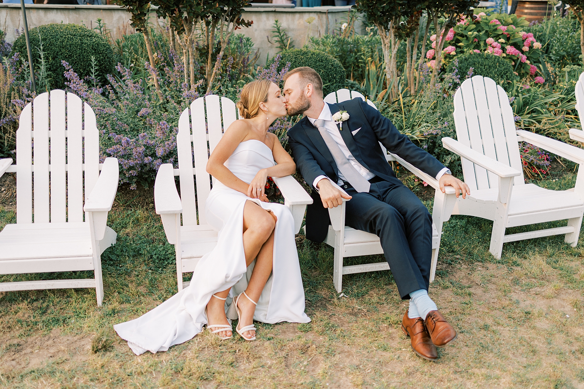 bride and groom kiss sitting in Adirondack chairs at Willow Creek Winery