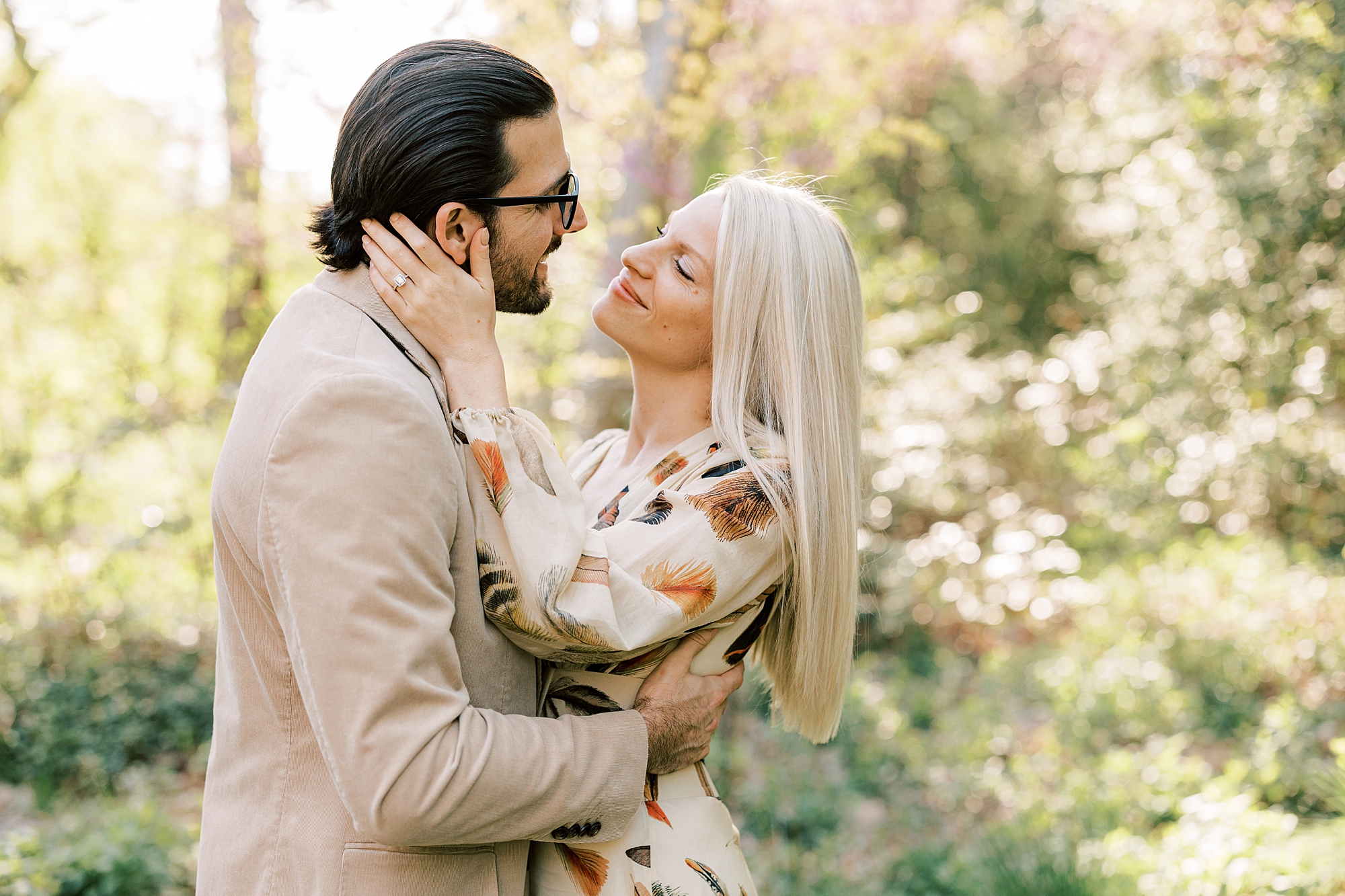 woman holds man's head looking at him during spring engagement session at Longwood Gardens