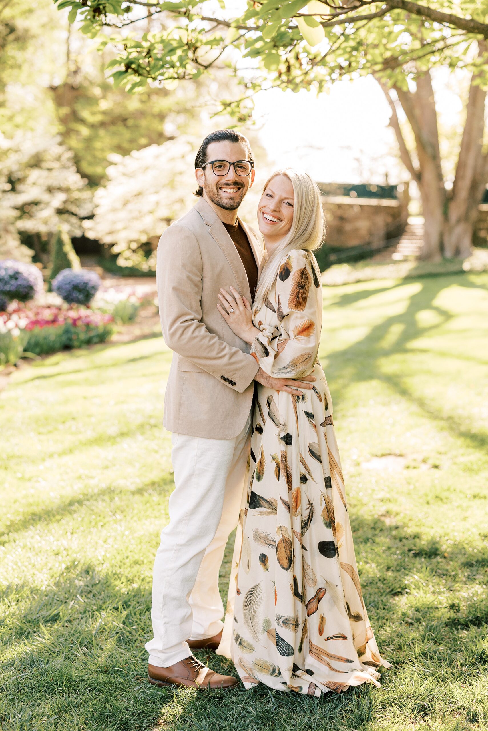 newlyweds hug on grass during spring engagement session at Longwood Gardens