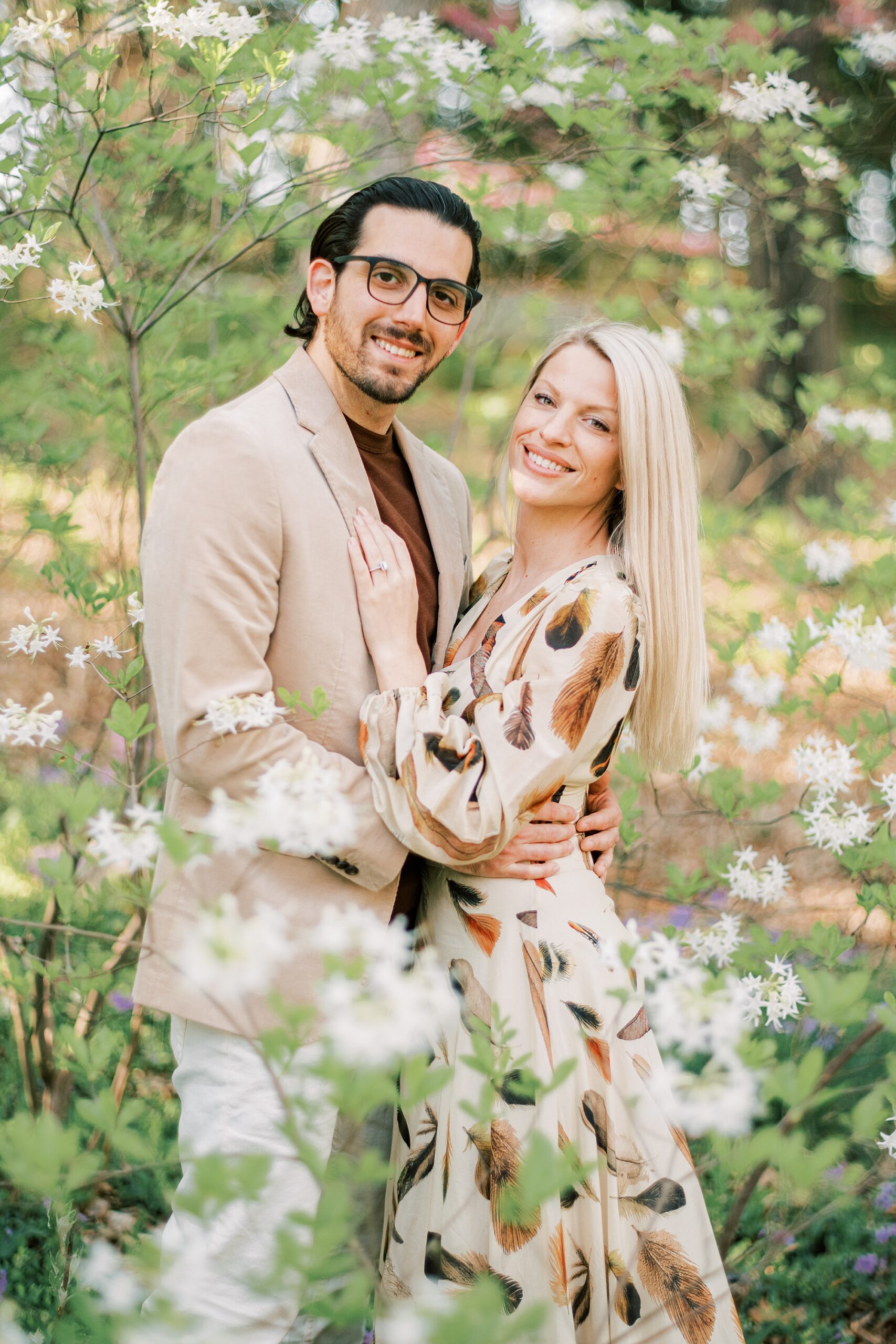 engaged couple hugs in white flowers during portraits at Longwood Gardens 