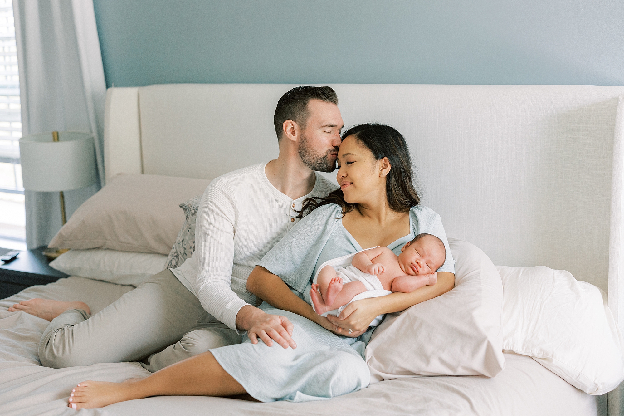 parents hug on bed with newborn son during newborn session in Cherry Hill NJ