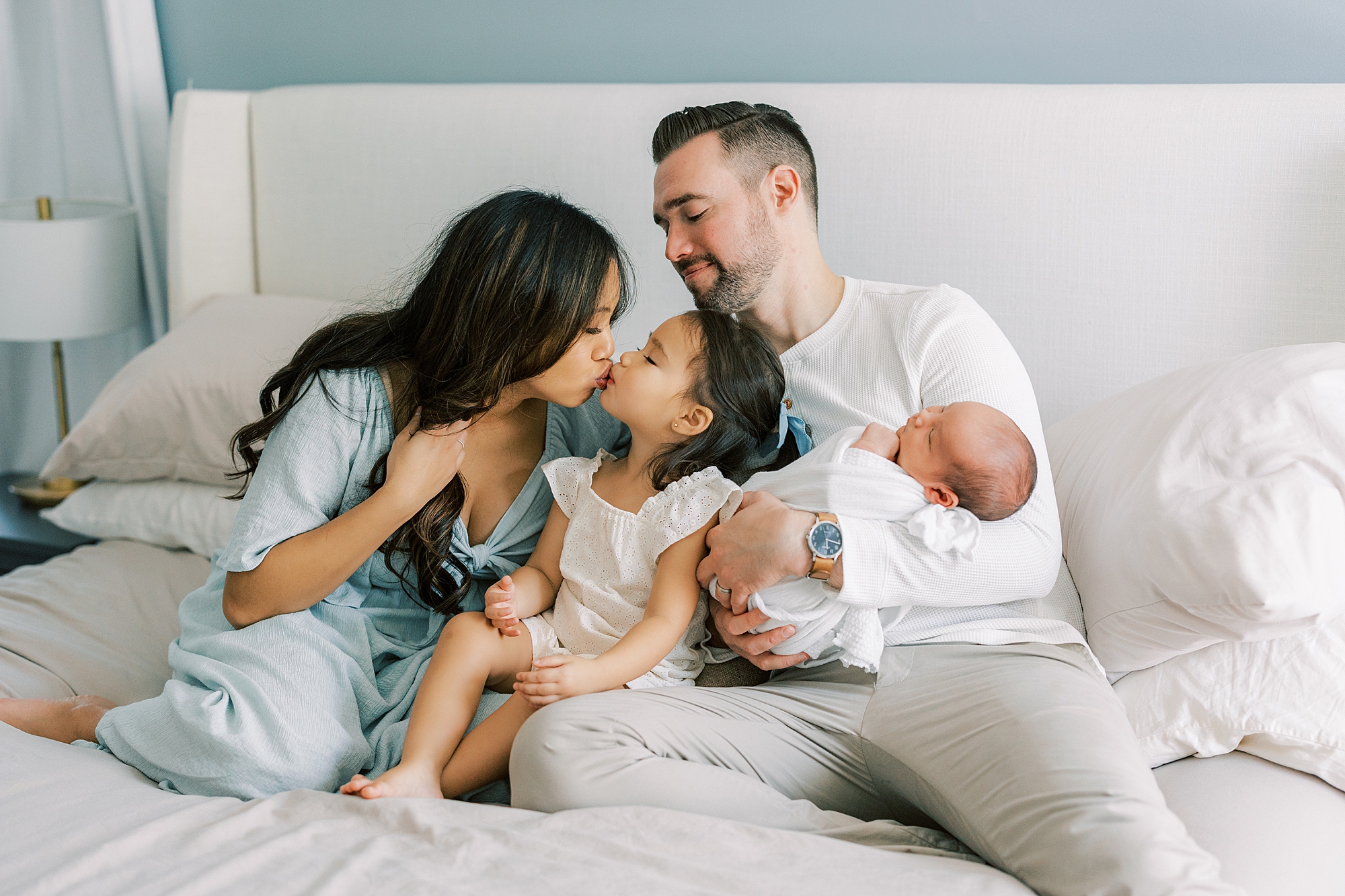 dad holds son while mom leans to kiss daughter during family photos at home in Cherry Hill NJ