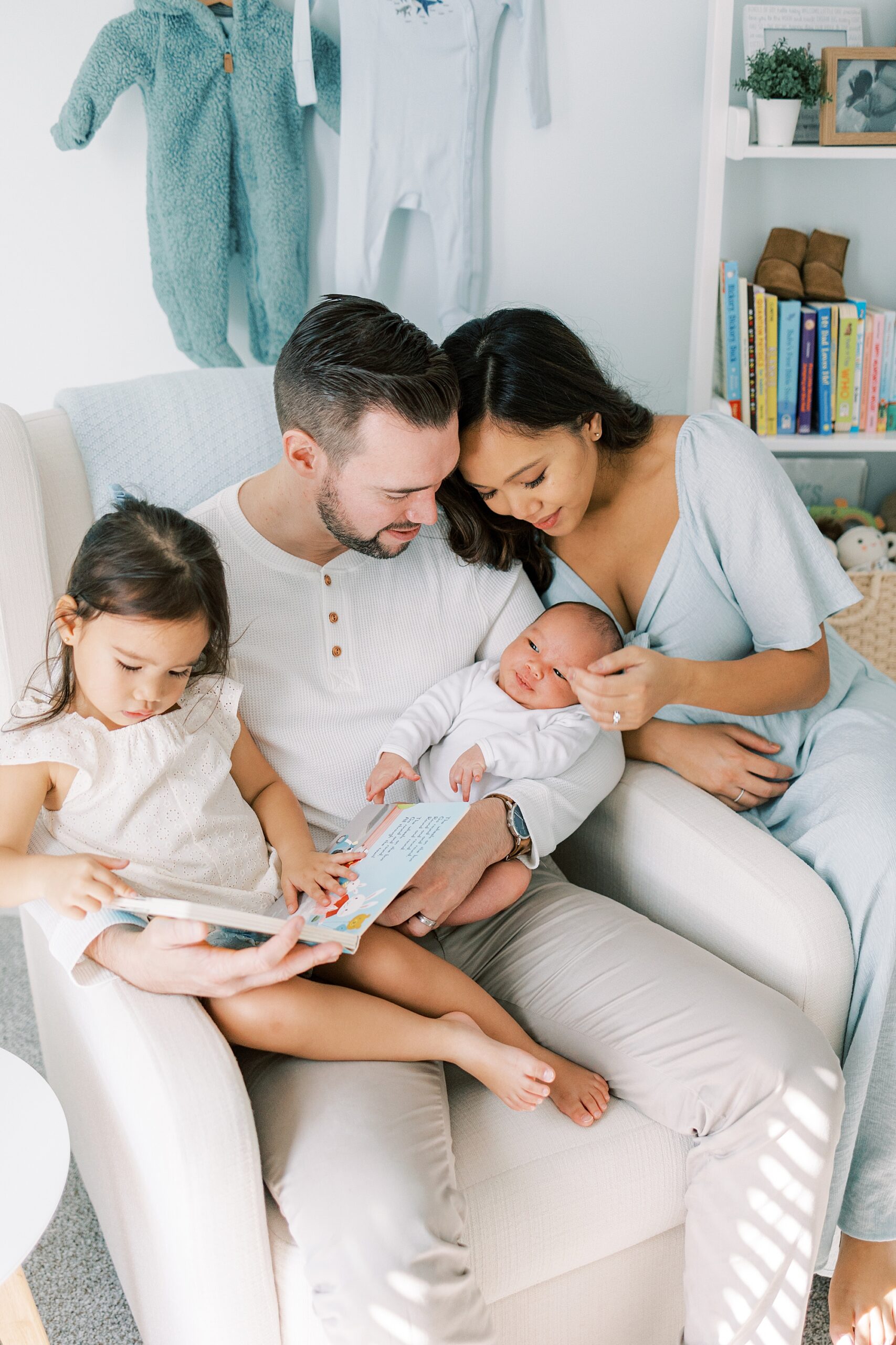 parents hold two children in rocker in nursery during lifestyle newborn portraits 