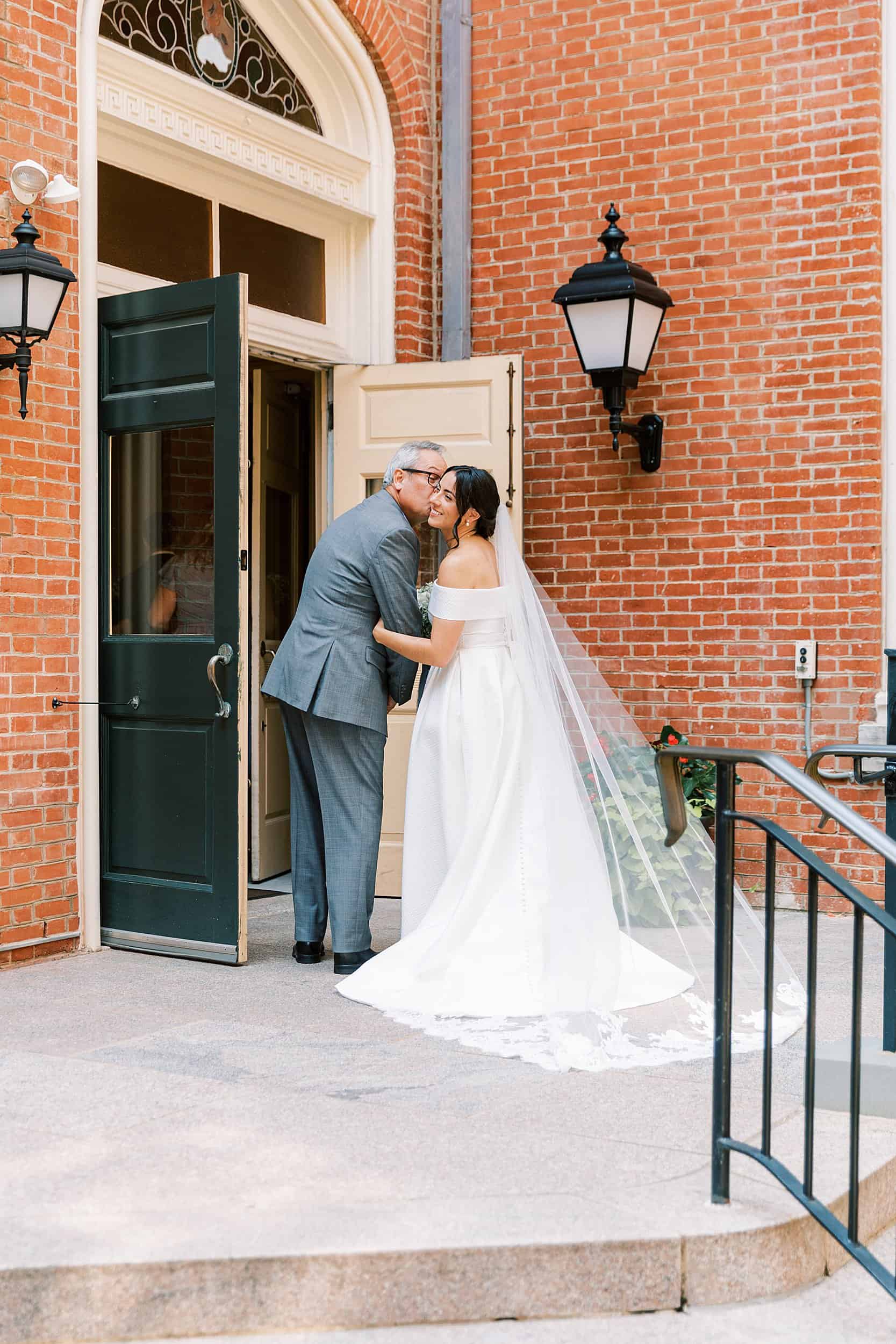 dad kisses his daughter on the cheek before walking her down the aisle at her Philadelphia wedding