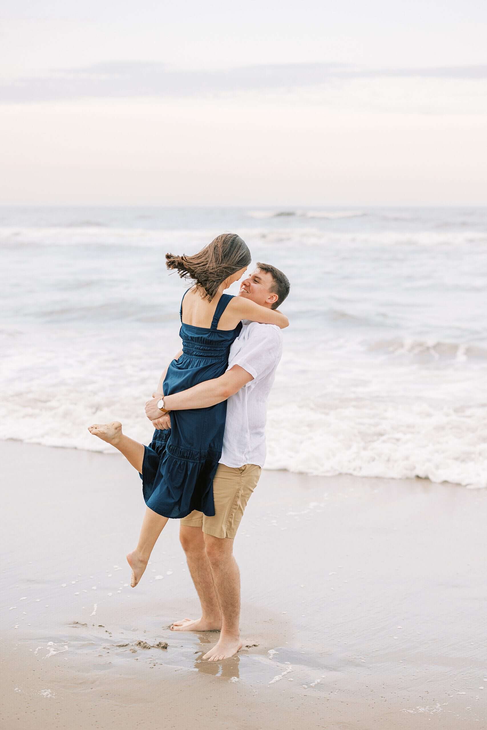 man dips bride on beach during Ocean City NJ engagement photos at sunset