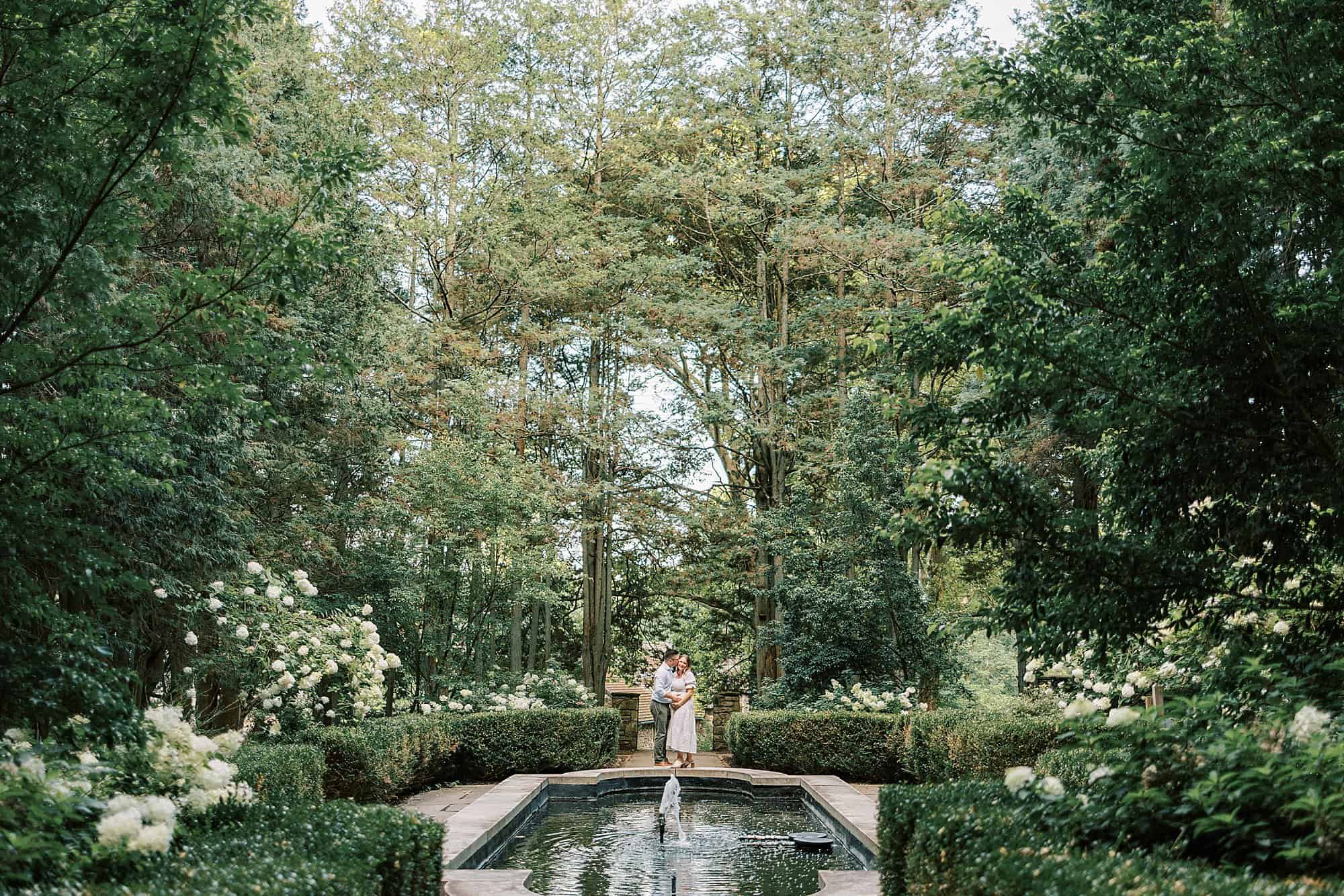 a wide image of a lush garden with a beautiful reflecting pool and fountain at Ridley Creek State Park 