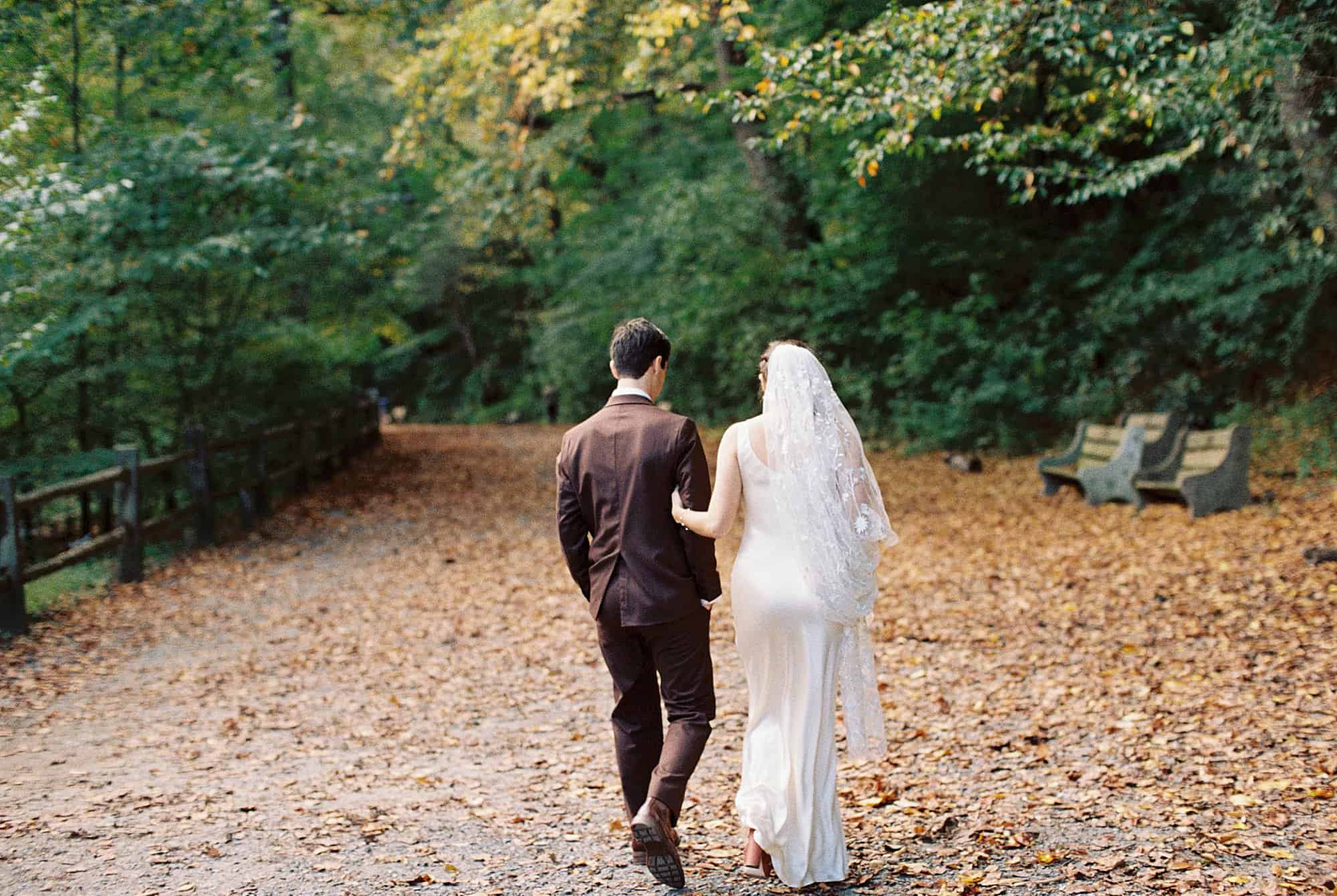 a bride and groom walk away on a bed of fall leaves at Valley Green Inn on their wedding day