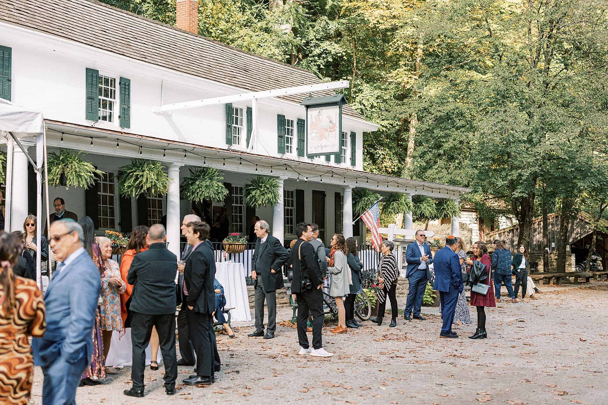 guests at a wedding gather outside valley green inn for cocktail hour