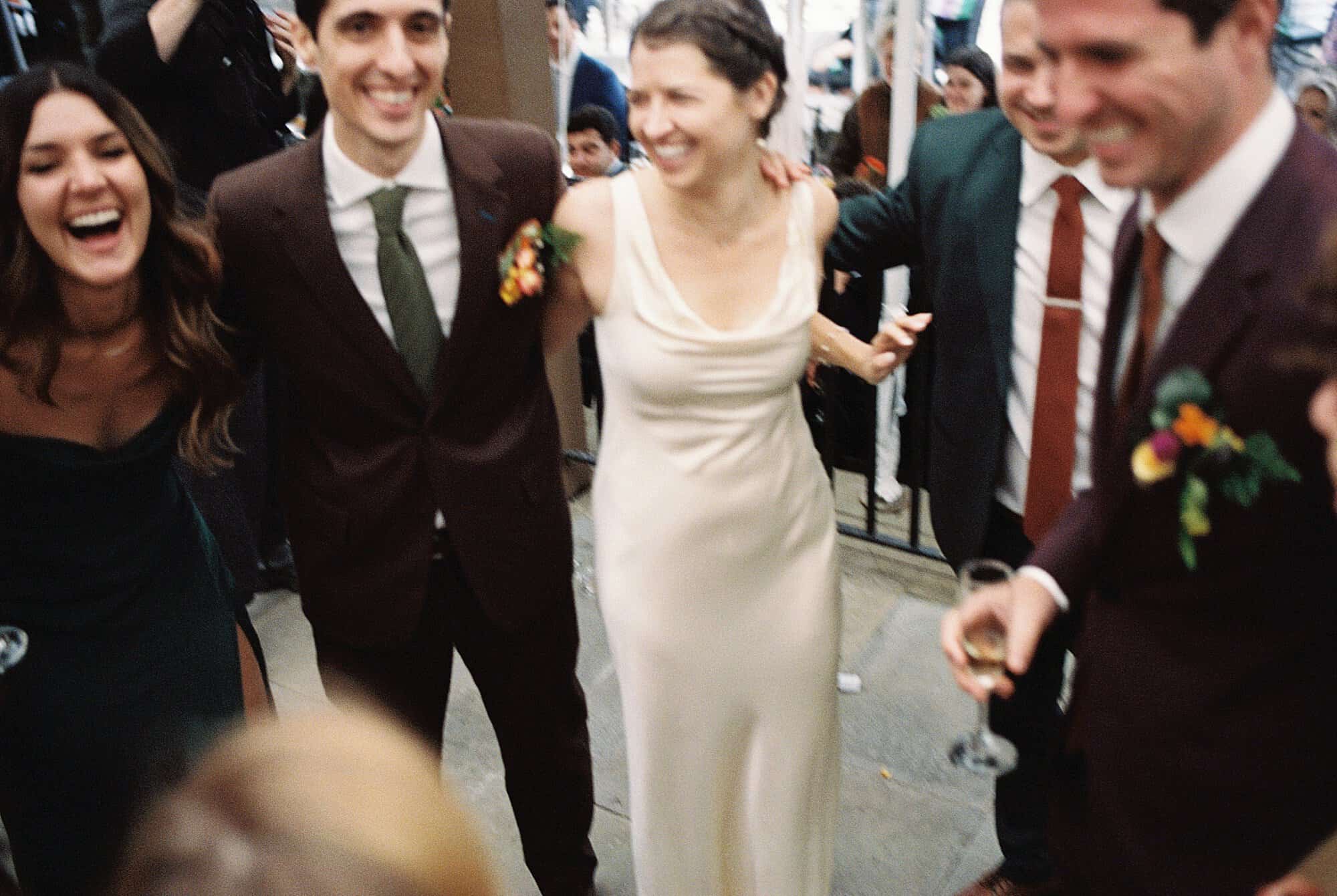 a blurry film photo of a bride and groom dancing and laughing with their bridal party during their Valley Green Inn wedding reception