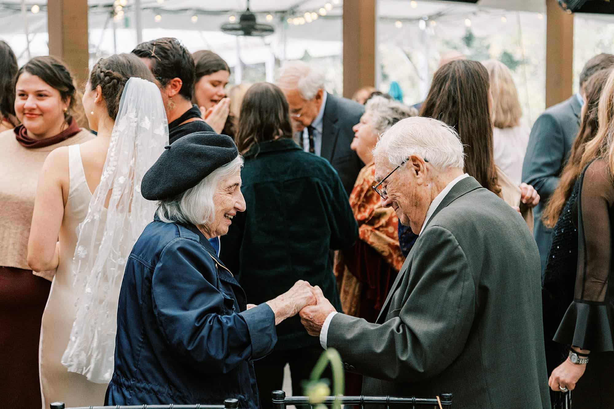 an older couple hold hands and dance together during a wedding celebration for their grand daughter in Philadelphia 