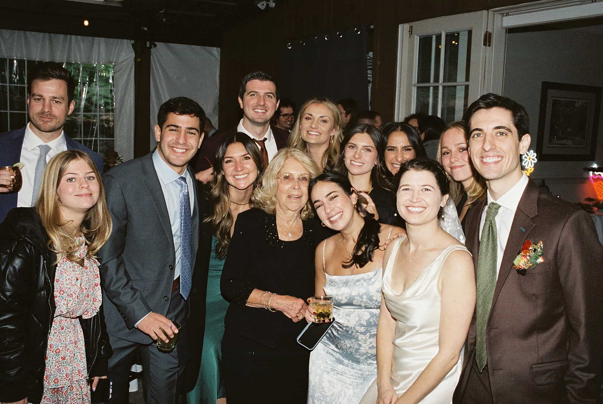 a direct flash style film photo of a grandmother and all of her adult grandchildren smiling at the camera during a wedding celebration in Philadelphia