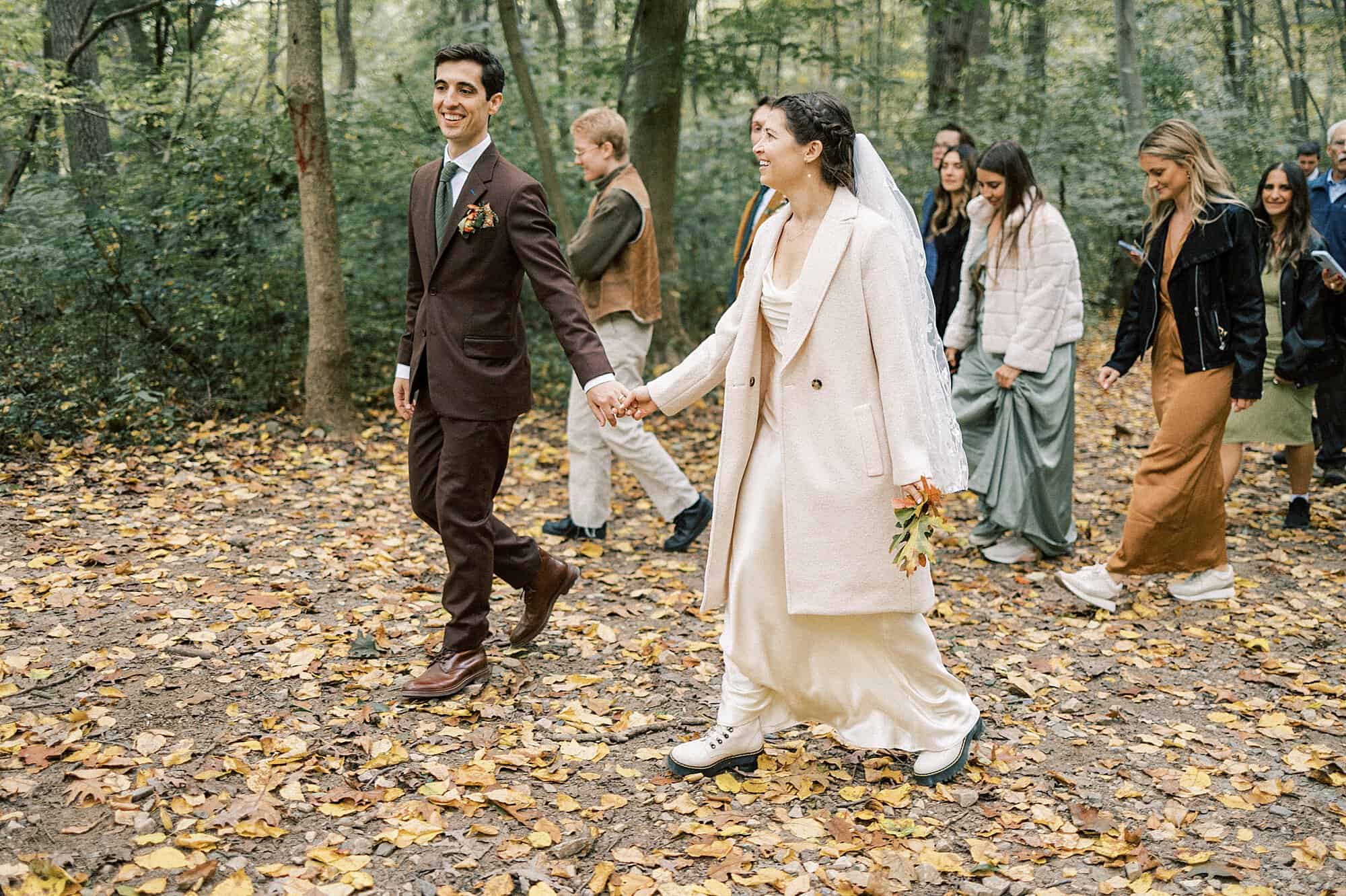 a bride and groom take their guests on fall hike after their ceremony