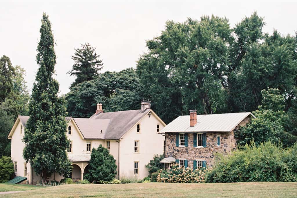 Historic cream farmhouse and stone cottage surrounded by mature trees on the grounds of Tyler Arboretum in Philadelphia, captured before a wedding at Tyler Arboretum.