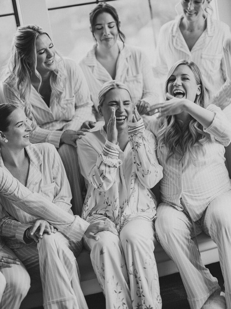 Black and white photo of the bride laughing with her bridesmaids while wearing matching pajamas during getting ready at The Ivy at Ellis Preserve