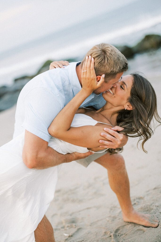 Romantic dip pose on Rehoboth Beach during coastal Delaware engagement photoshoot